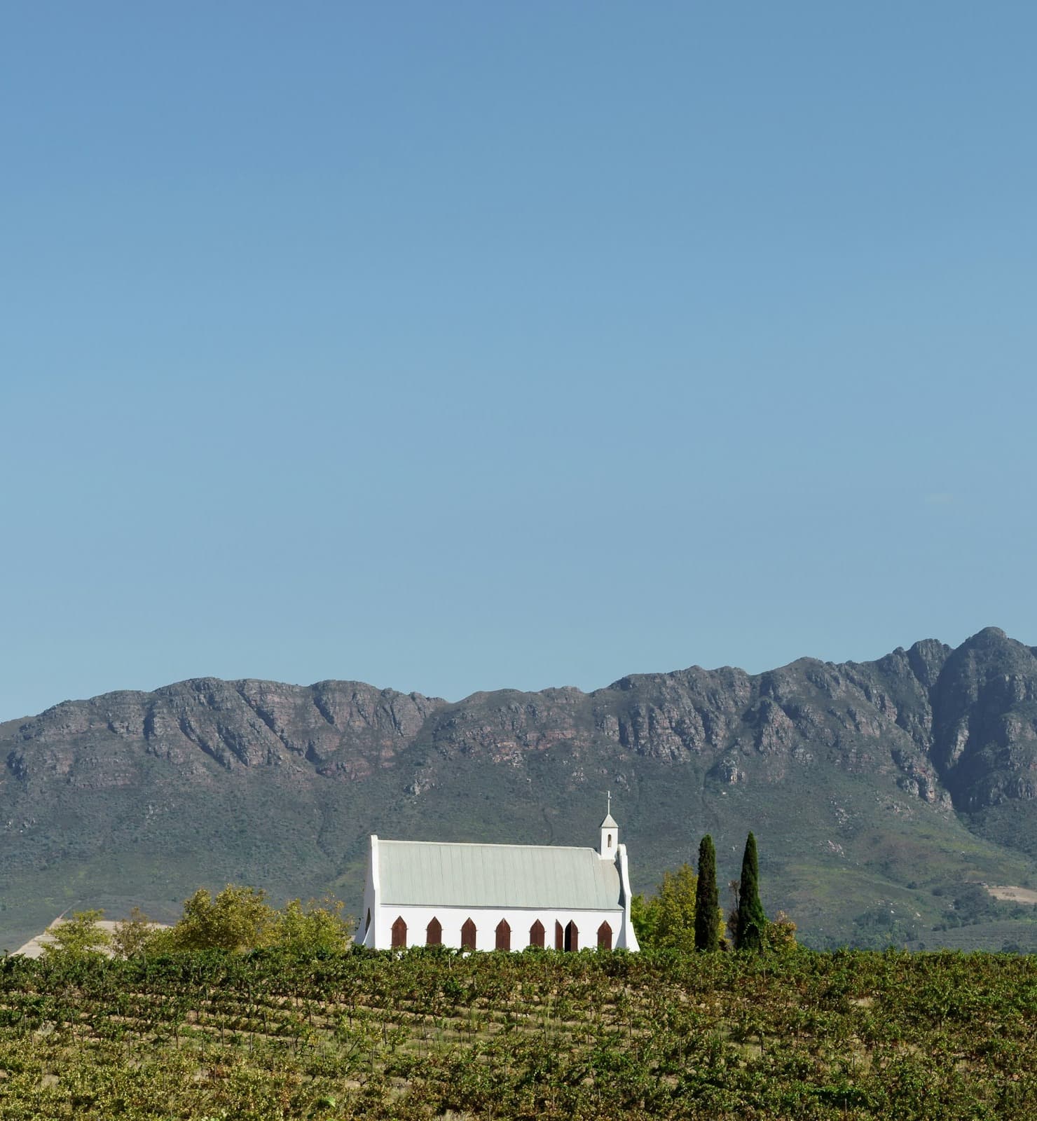 A church in the middle of a field with mountains in the background at Tulbagh, South Africa.