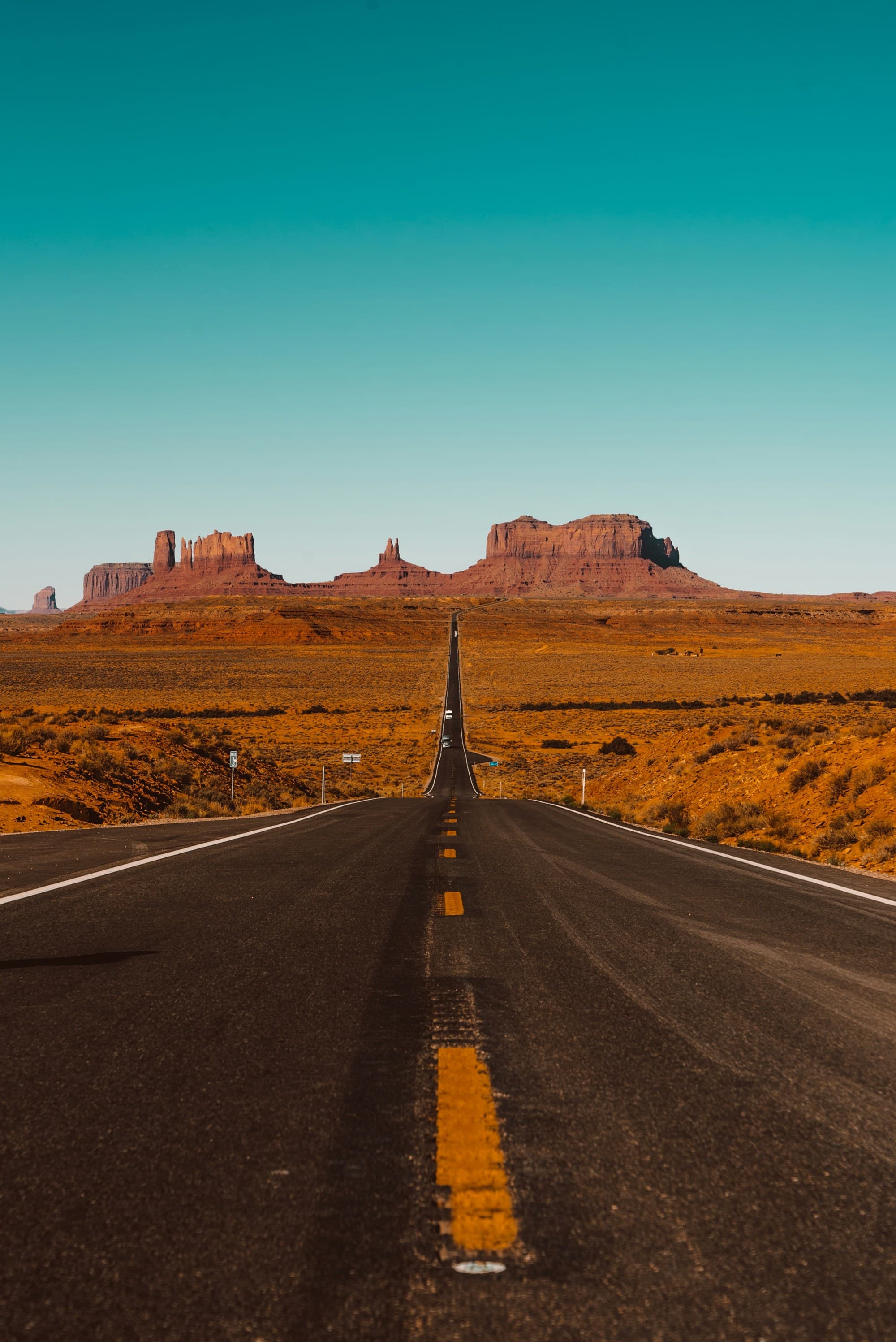 A road leading towards red rock formations.