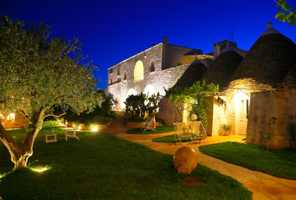 A courtyard with foliage next to a beautifully lit building