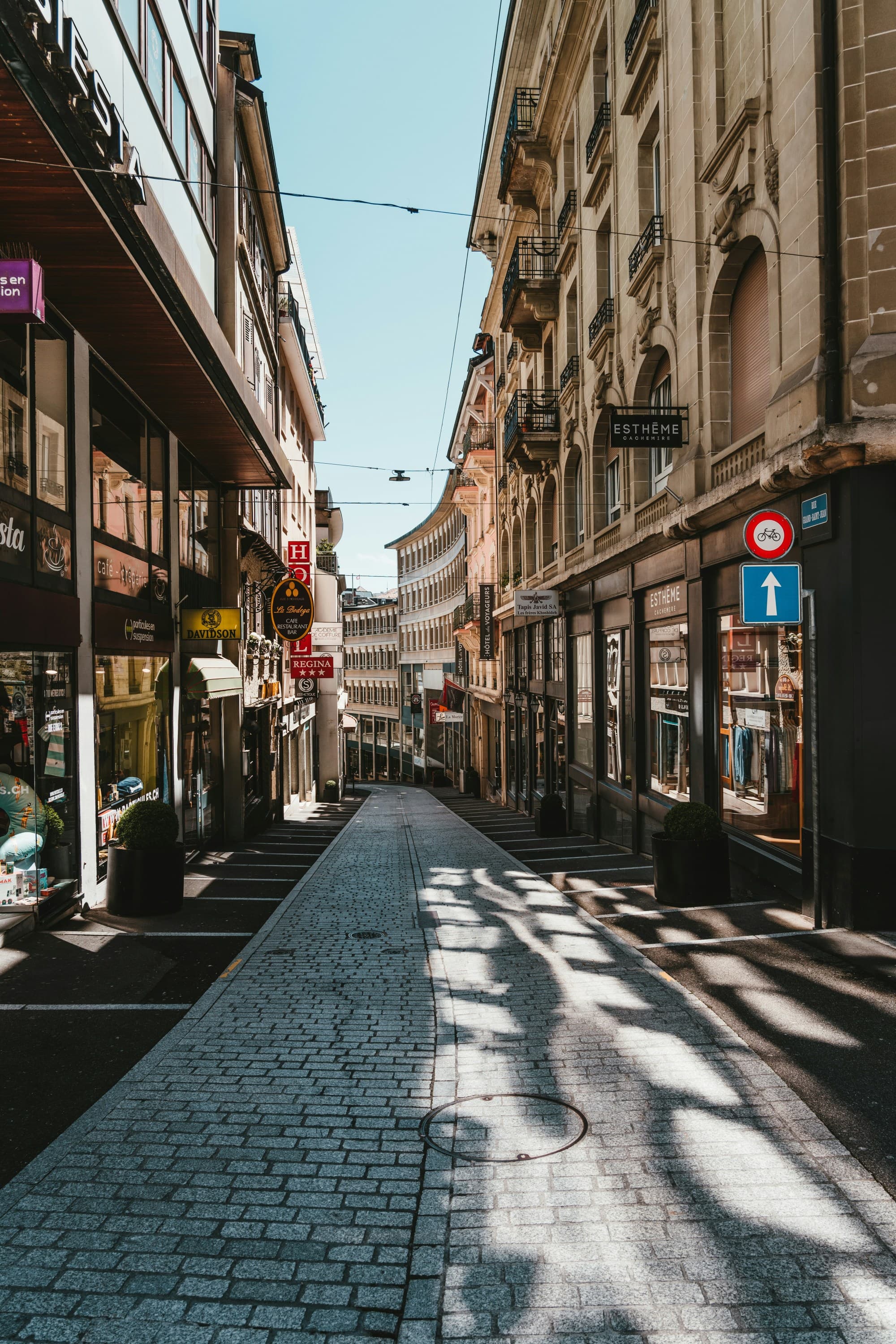 A picture of cars parked on the sidewalk near buildings during the daytime.