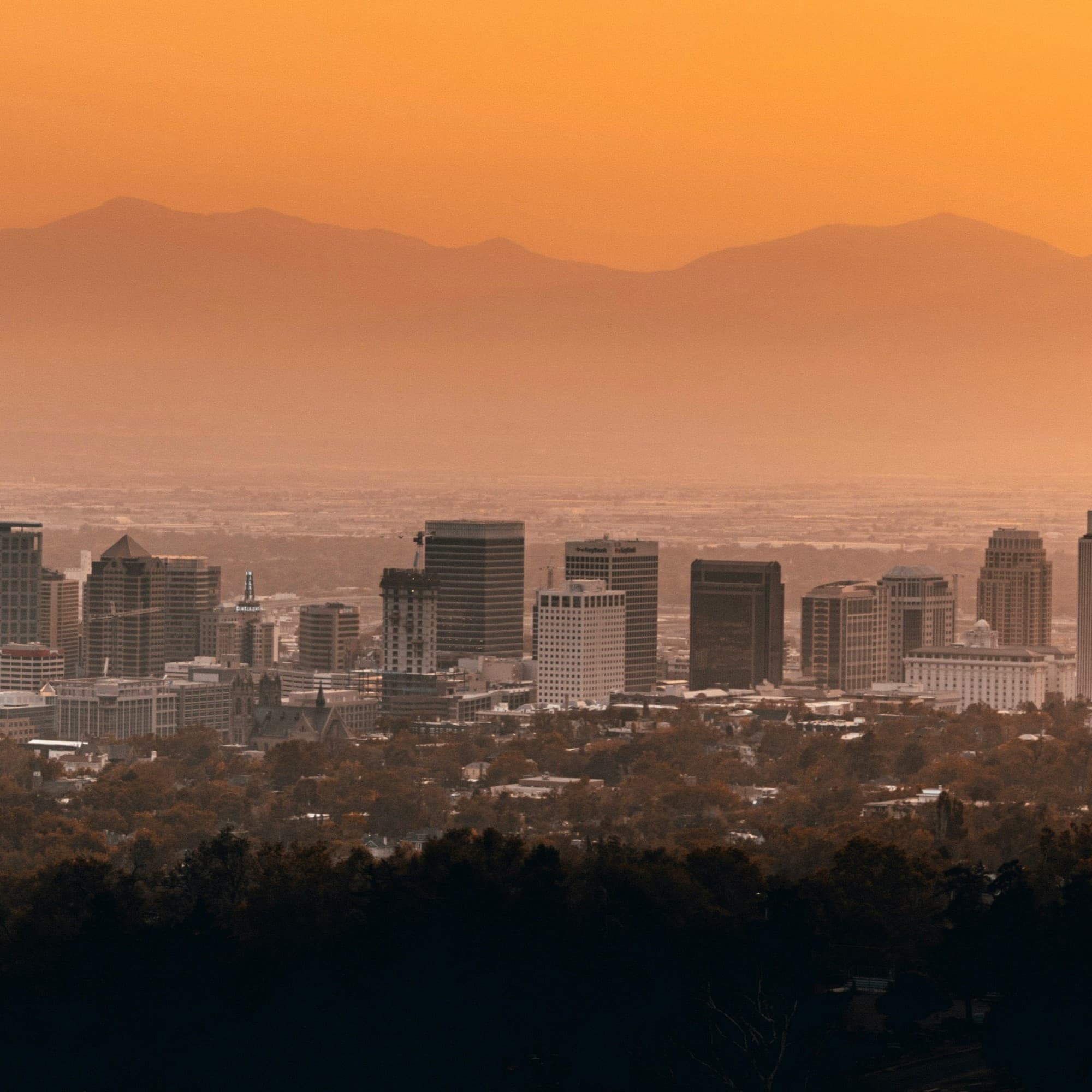 A city skyline with buildings at sunset.