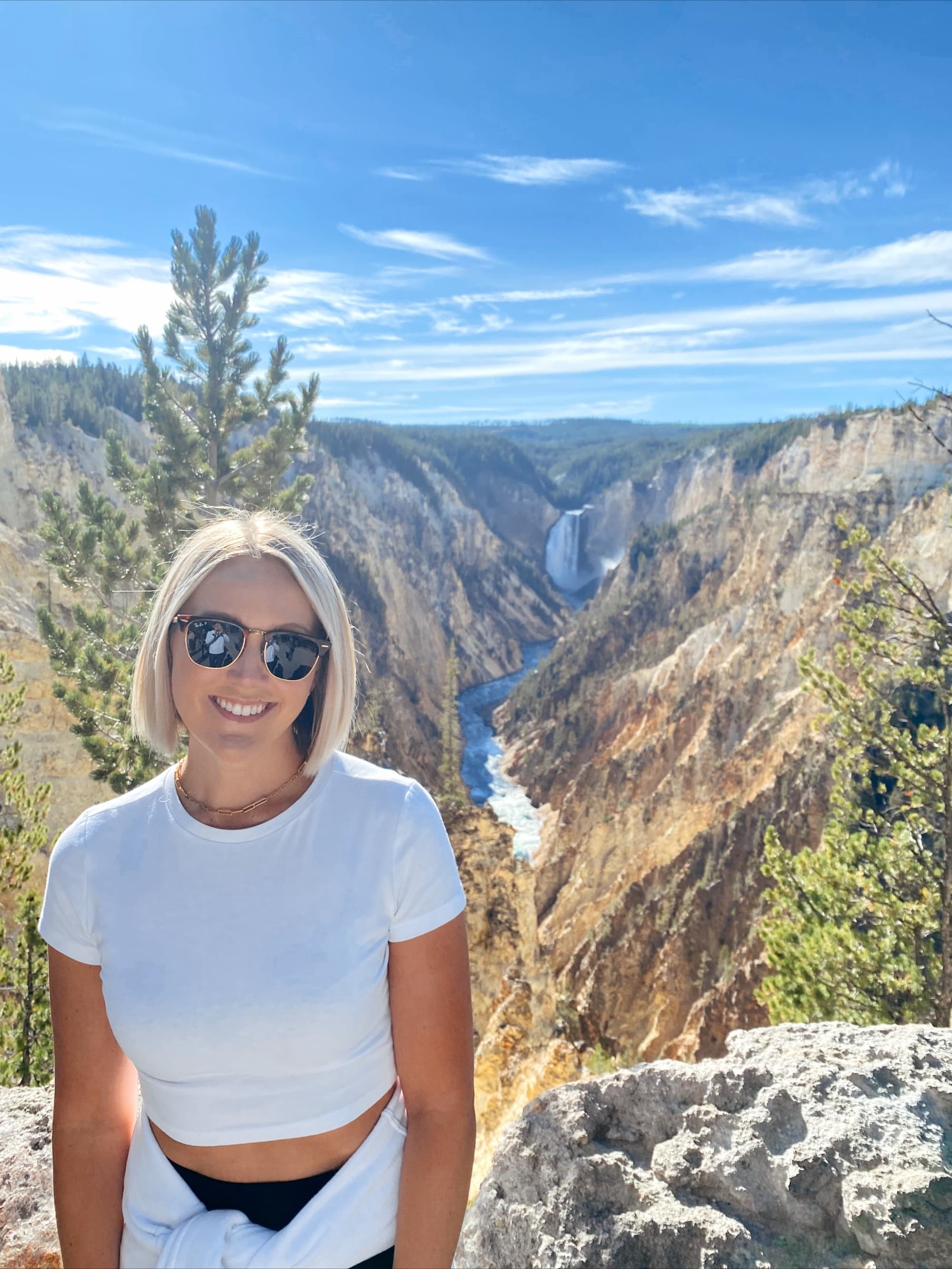 Woman with glasses standing in front of a mountain scape.