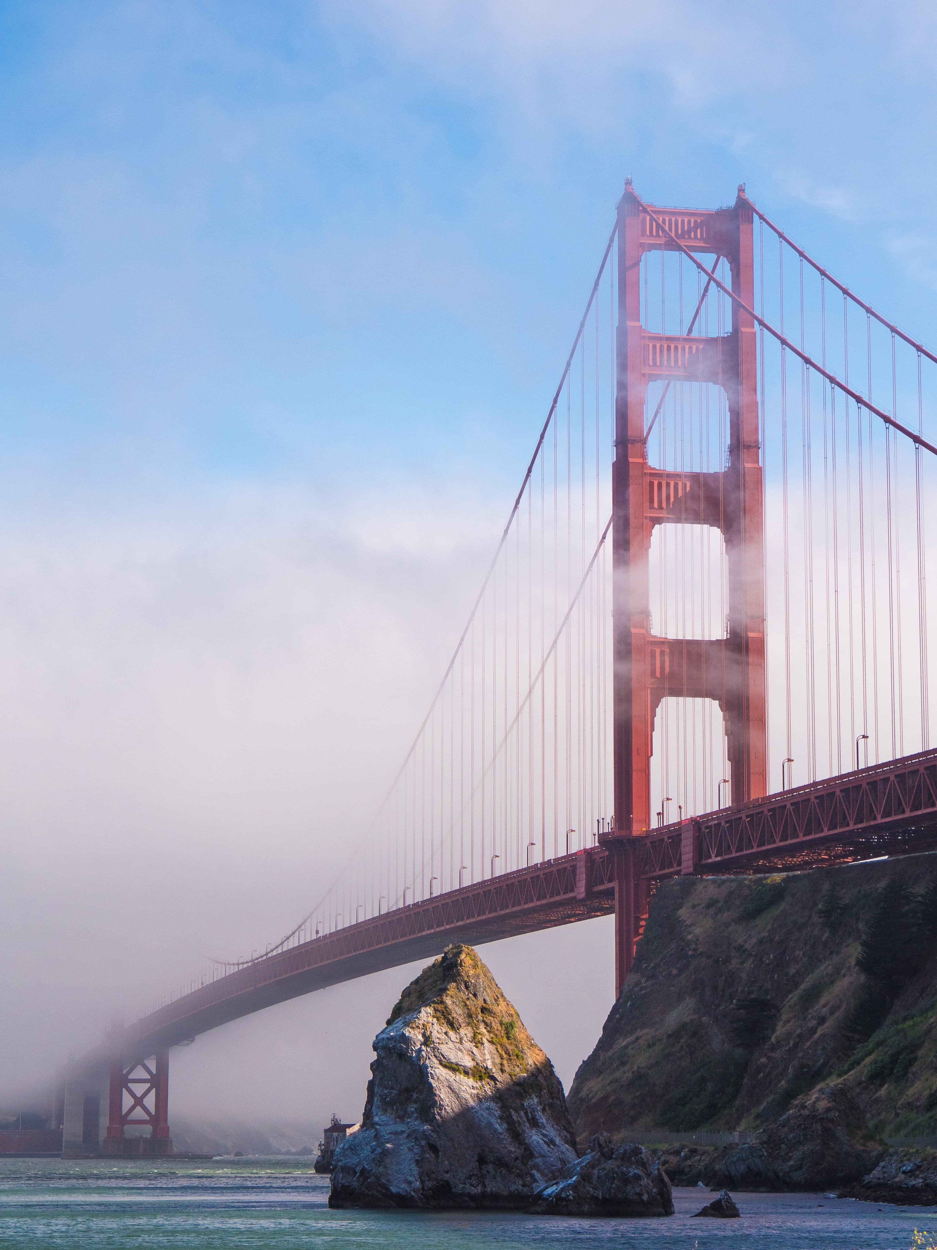 red bridge over body of water with foggy skies