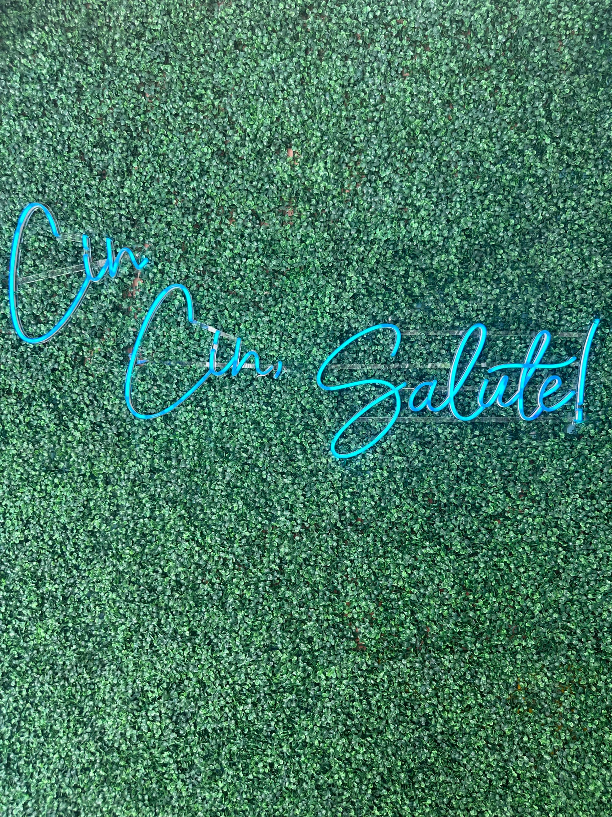 A grass wall with a blue neon sign