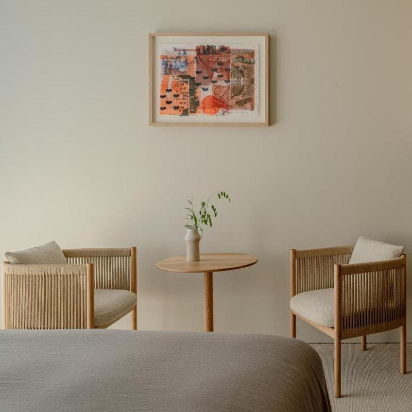 two wooden cushioned chairs in a serene minimalist bedroom