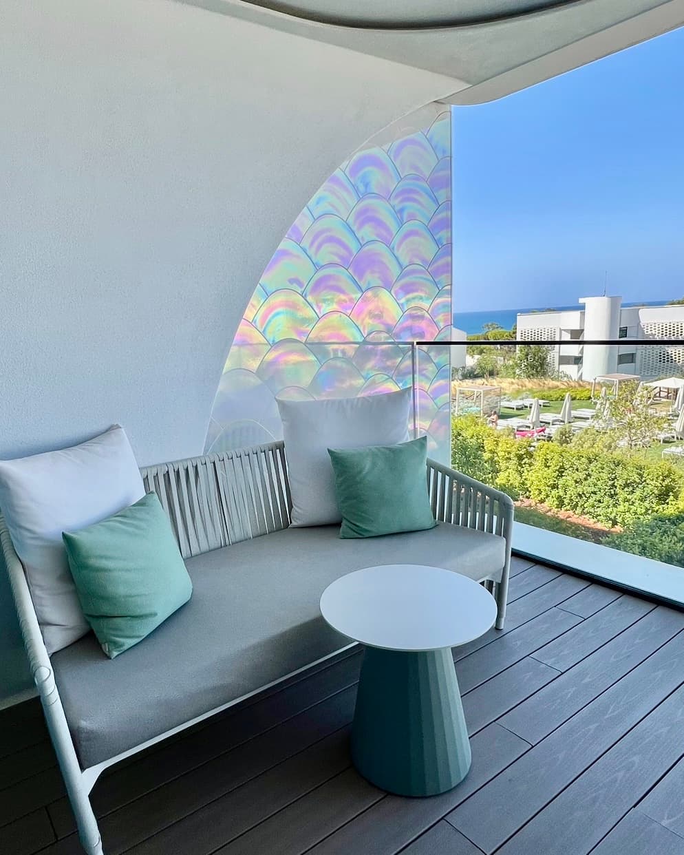 A hotel patio with a grey sofa with white and green pillows