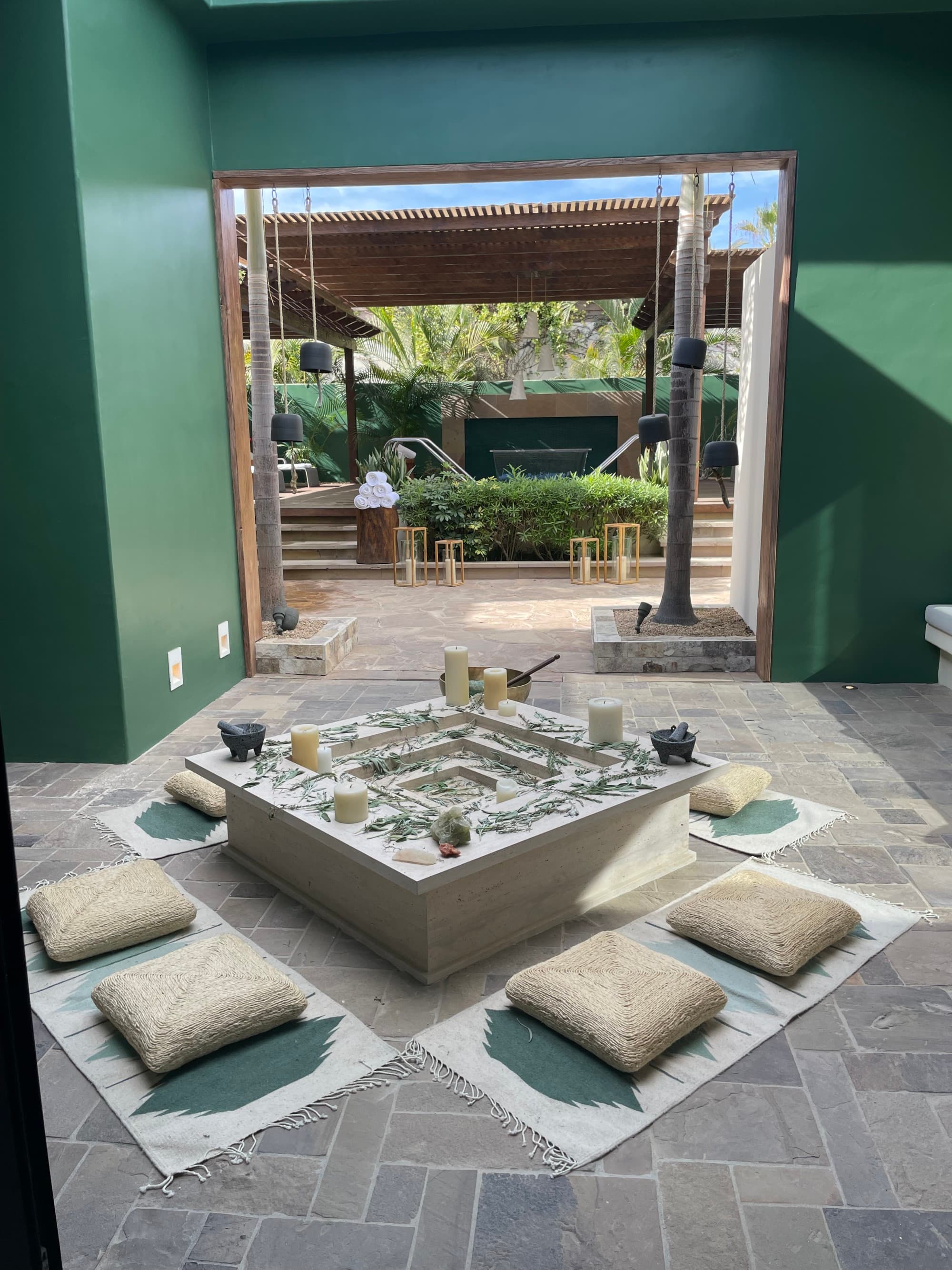 An outdoor patio with a tiered table in the middle surrounded by green-painted walls