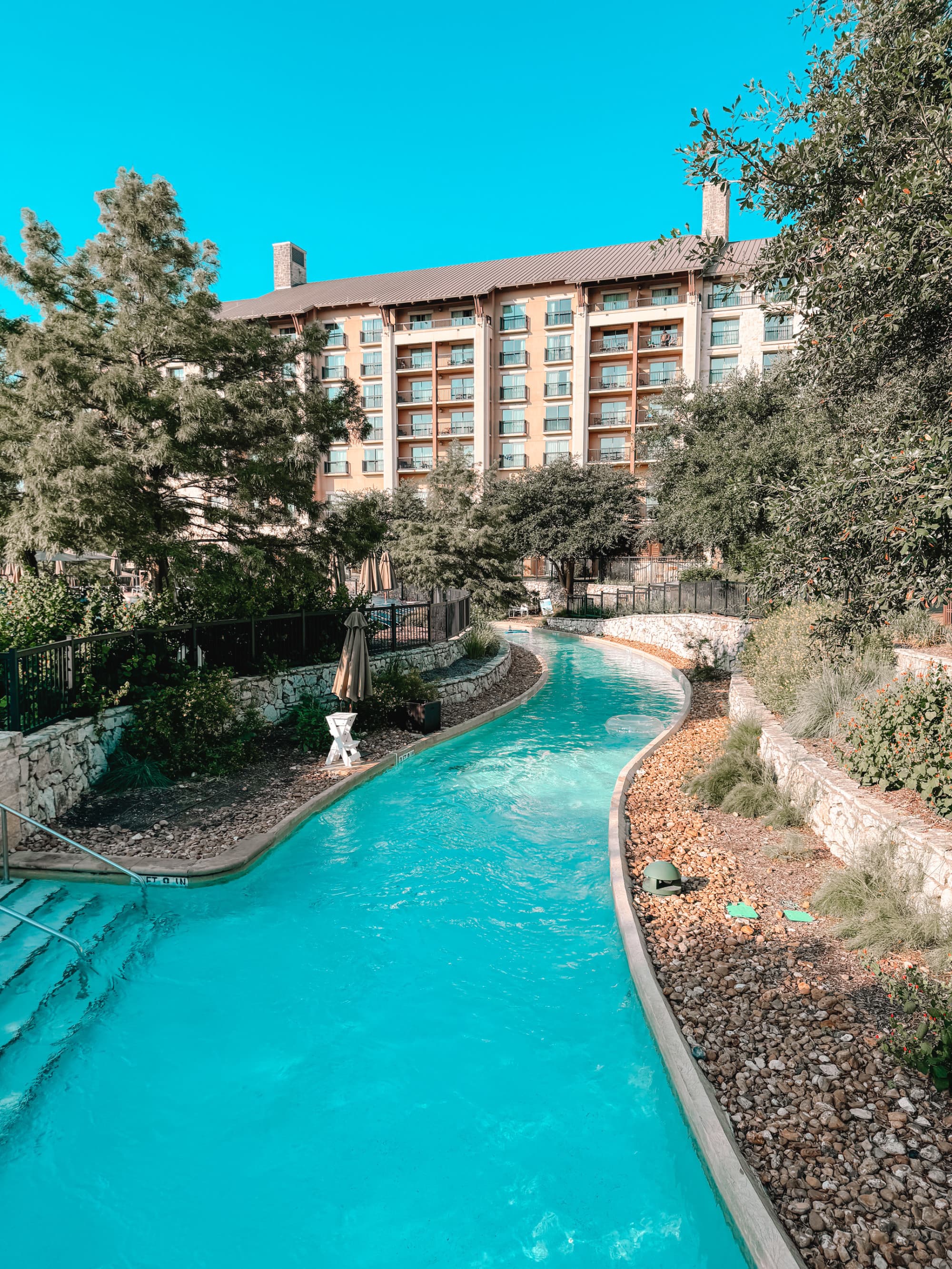 A lazy river winds its way through trees and foliage providing shade on a sunny day.