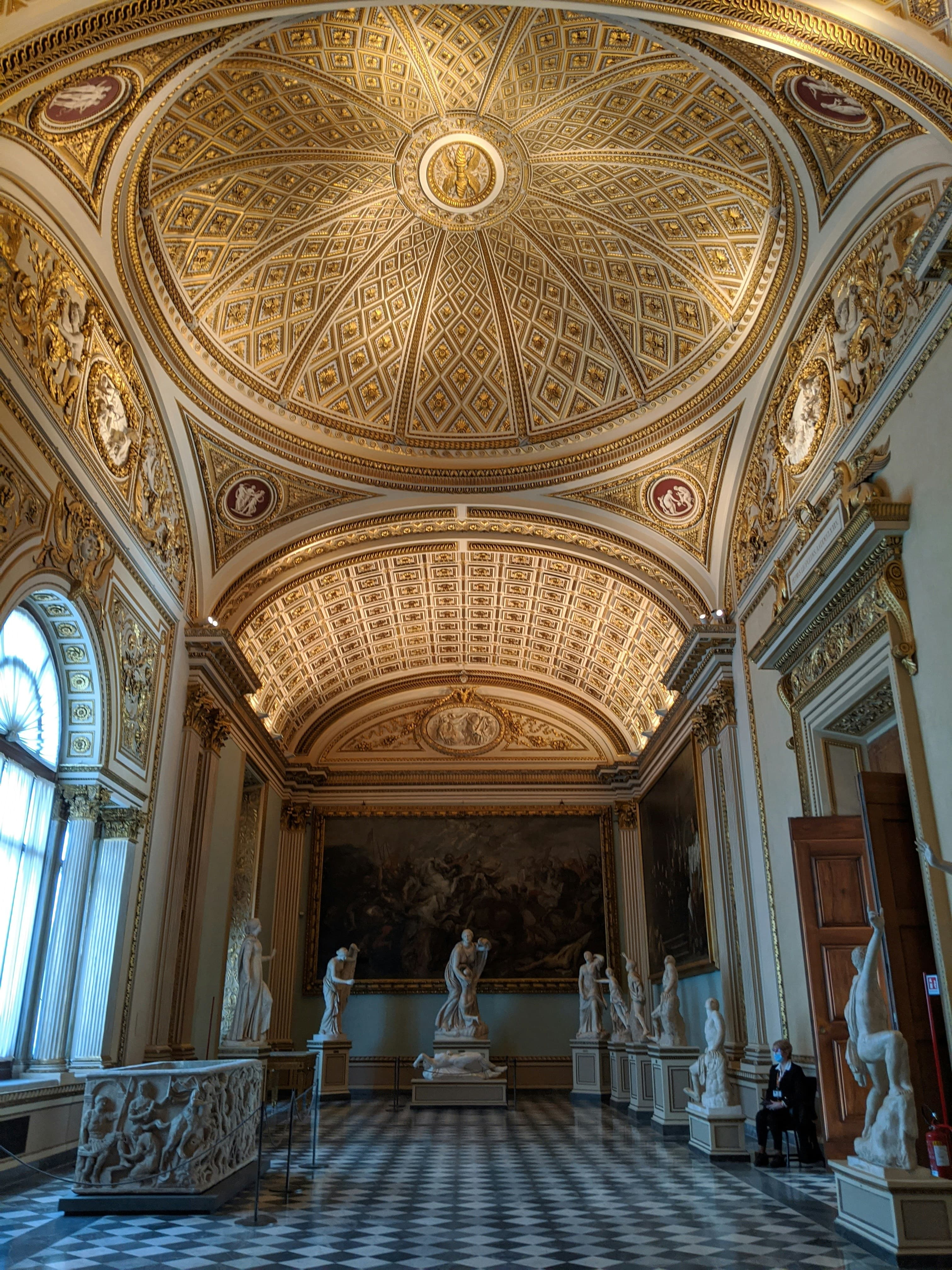 arched ceiling in a museum with colorful ceiling details and tiled floor and statues