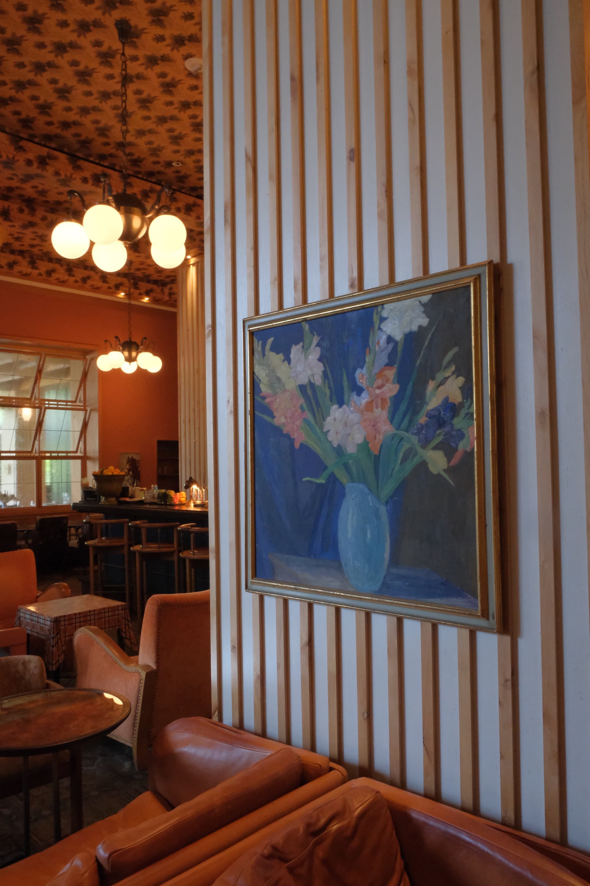 Beautiful wallpaper and art by local artists decorate a wall in the dining area with rich furnishings on a sunny day.