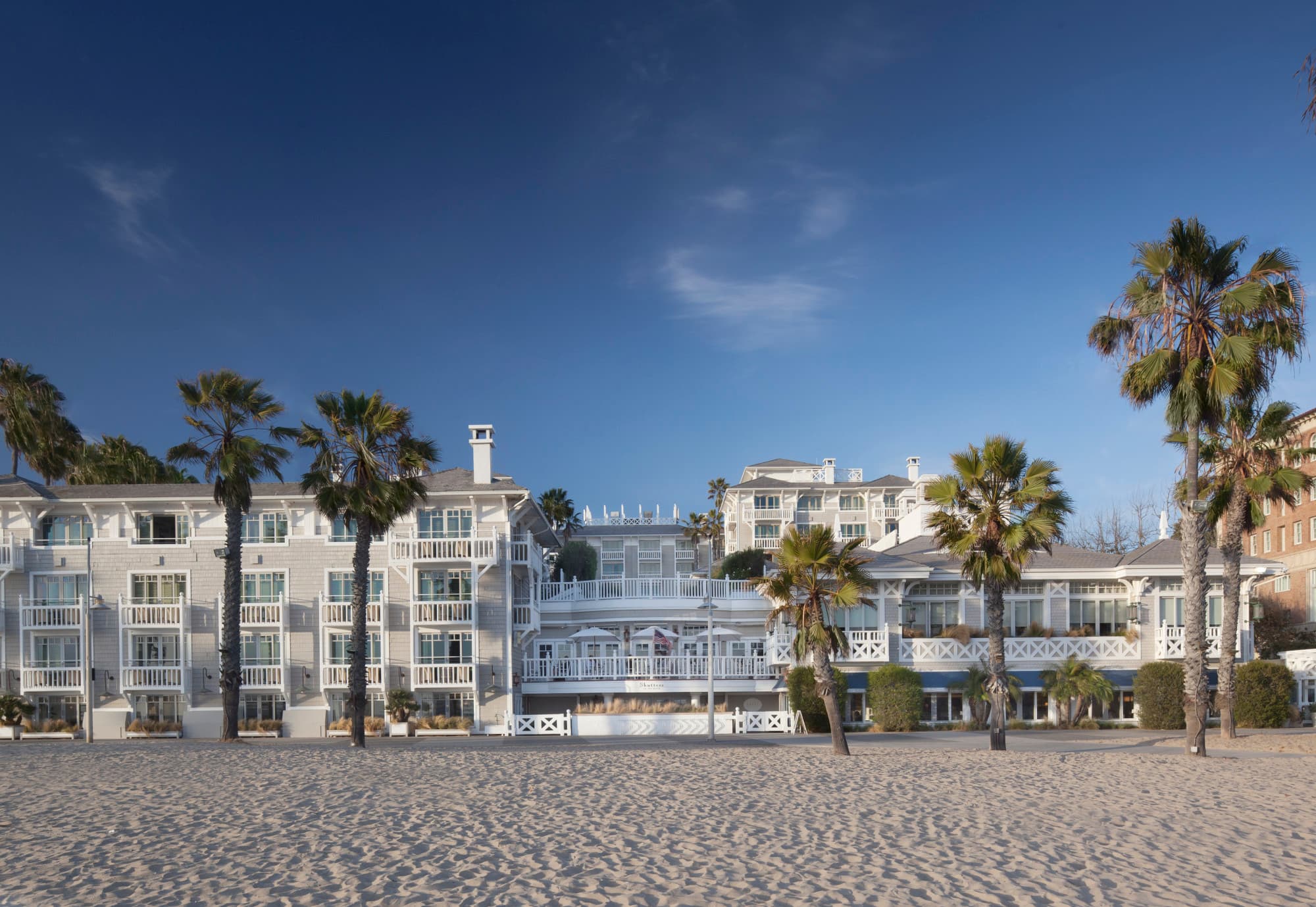 exterior of a beachfront hotel with windows surrounded by white shutters