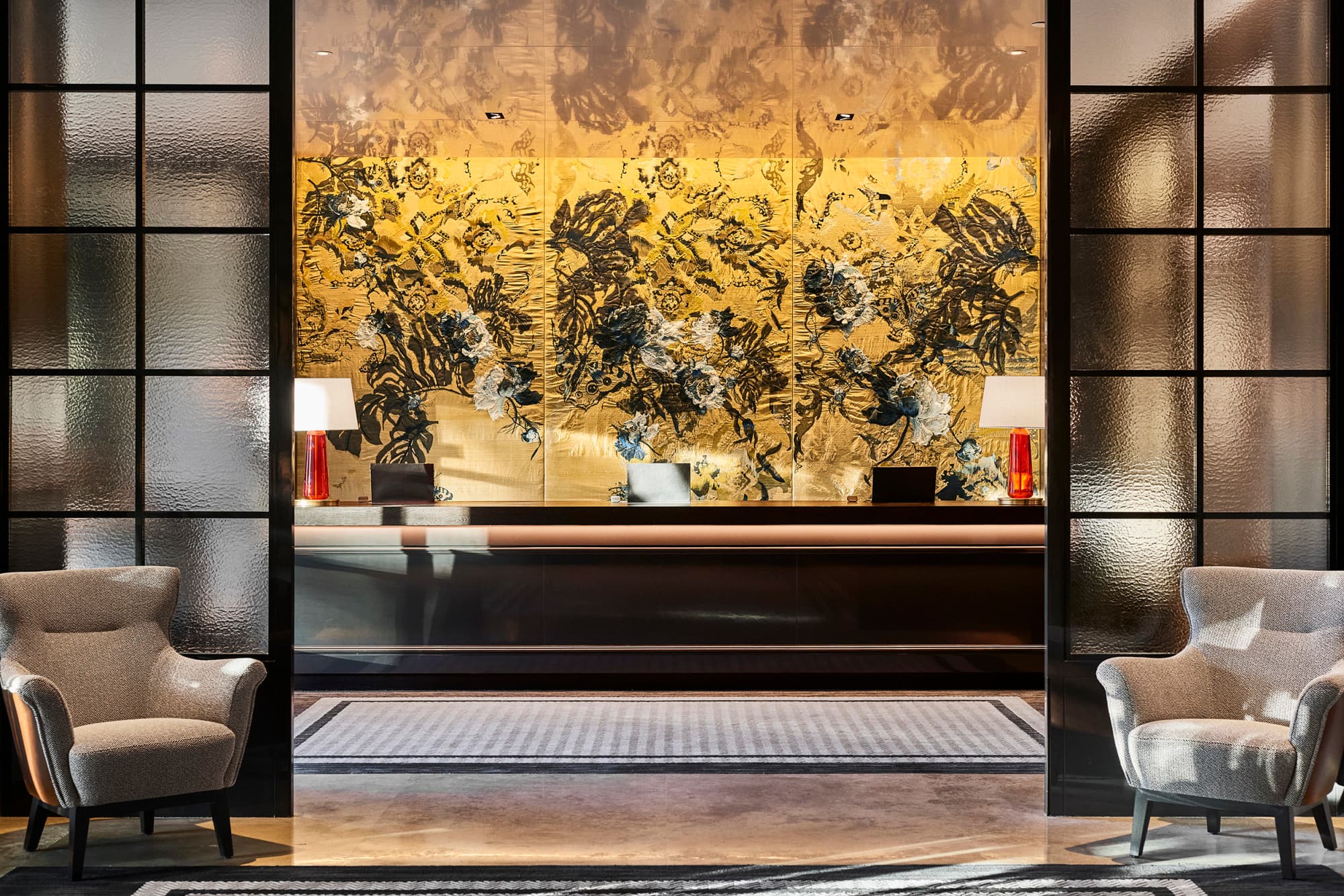 ornate reception desk in front of an illuminated yellow mural