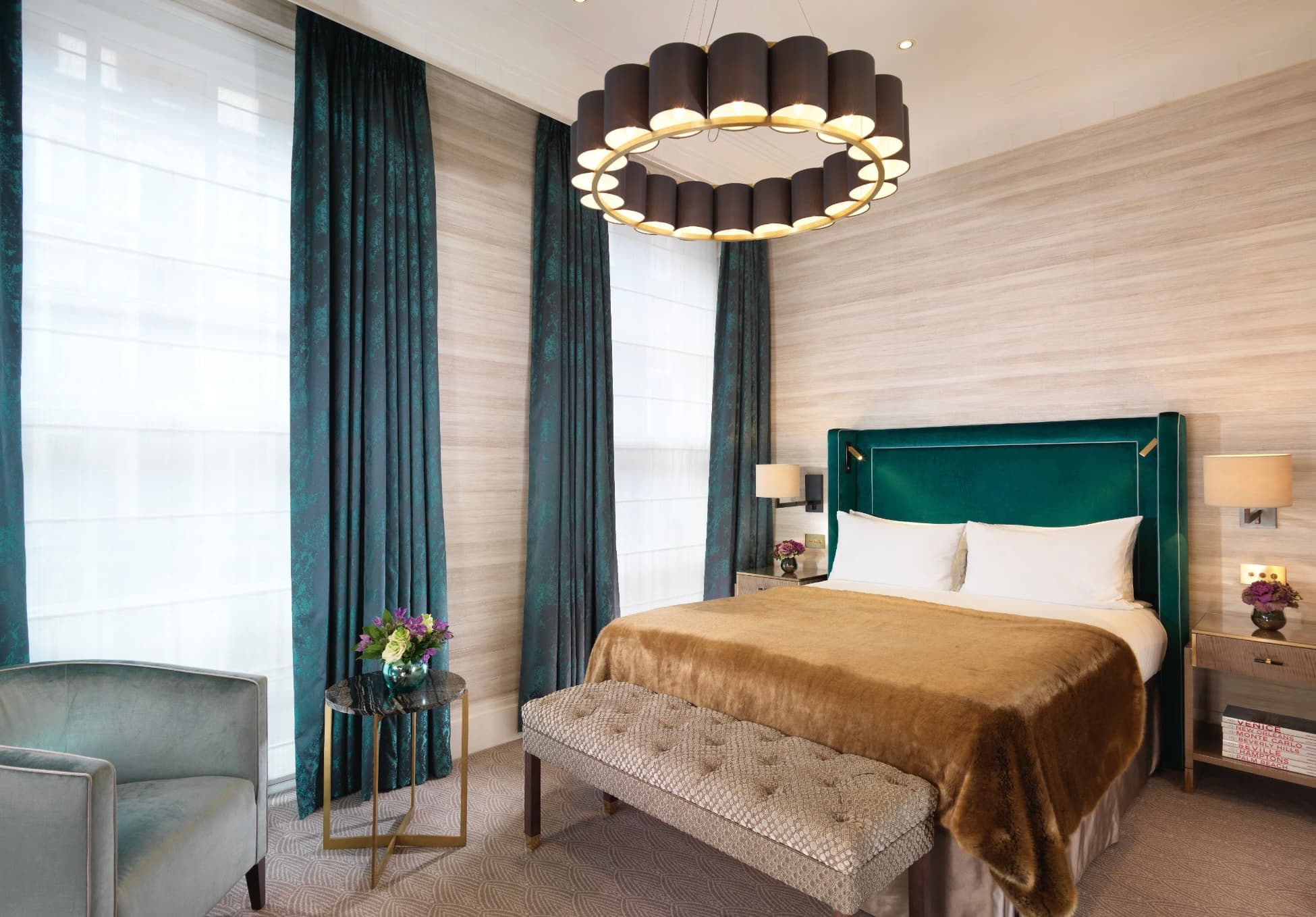 bedroom with round chandelier and dark green velvet drapes and headboard