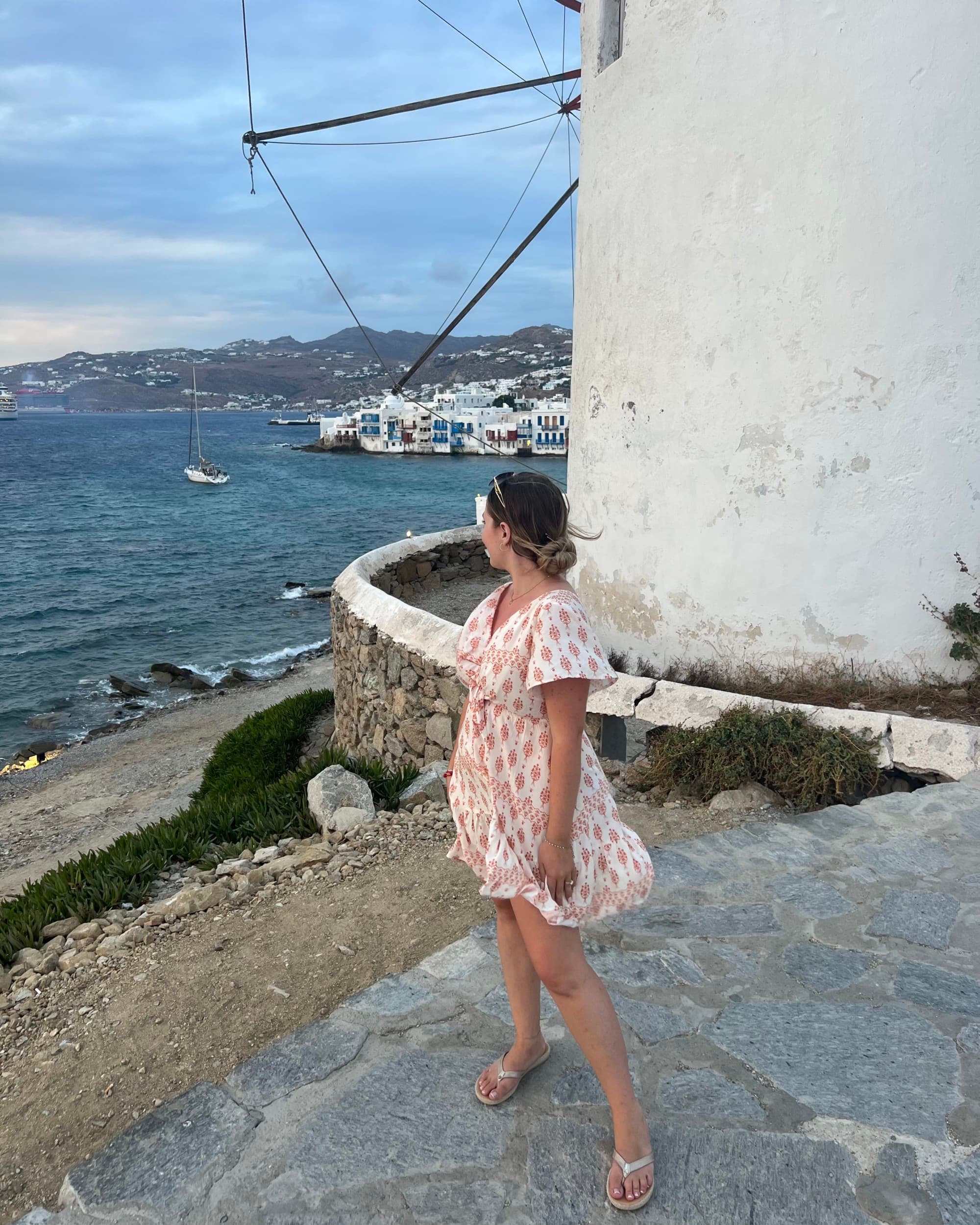 Woman in a white dress poses in front of a windmill.