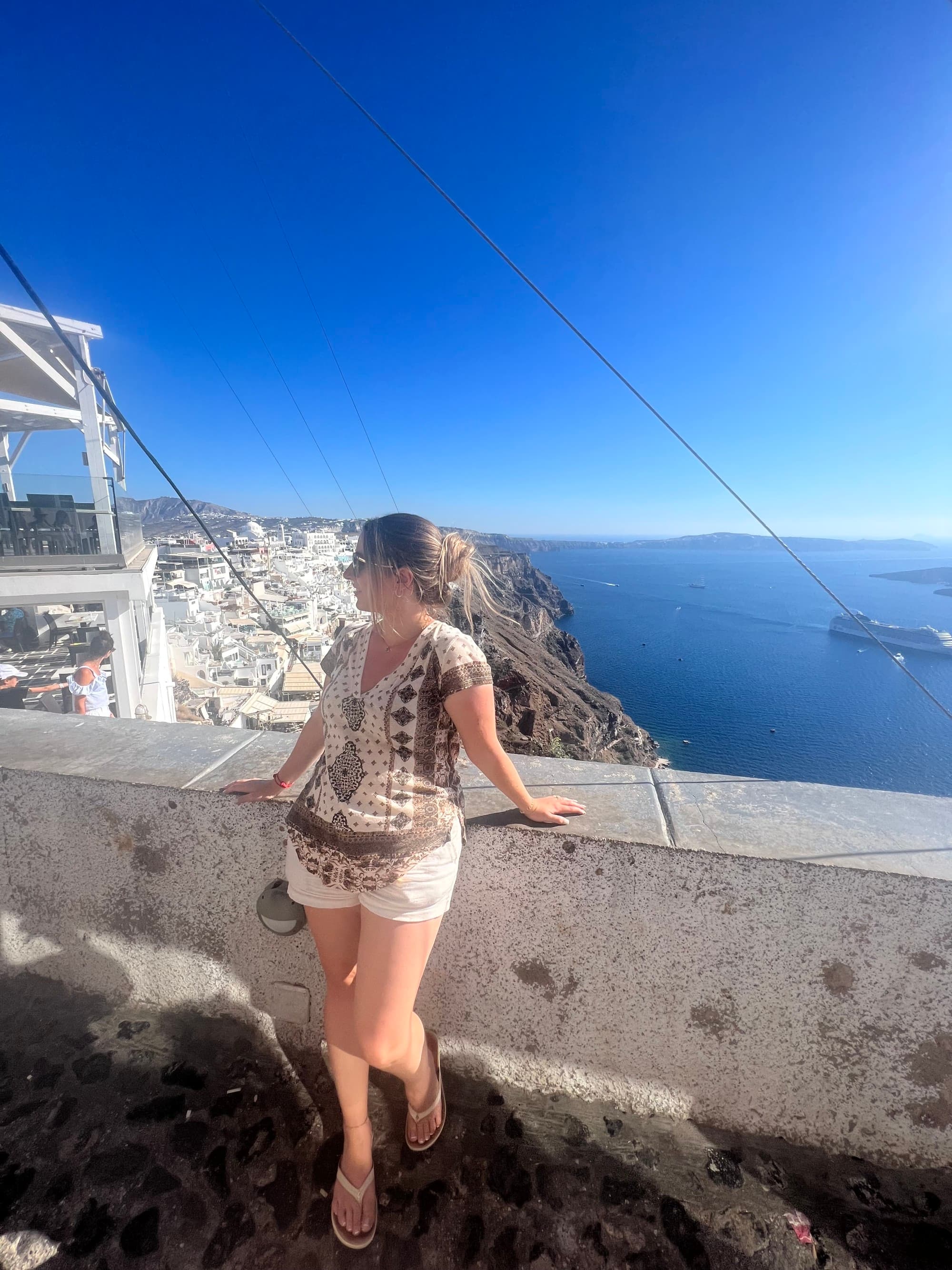 Advisor sits on a wall with a blue ocean behind her.