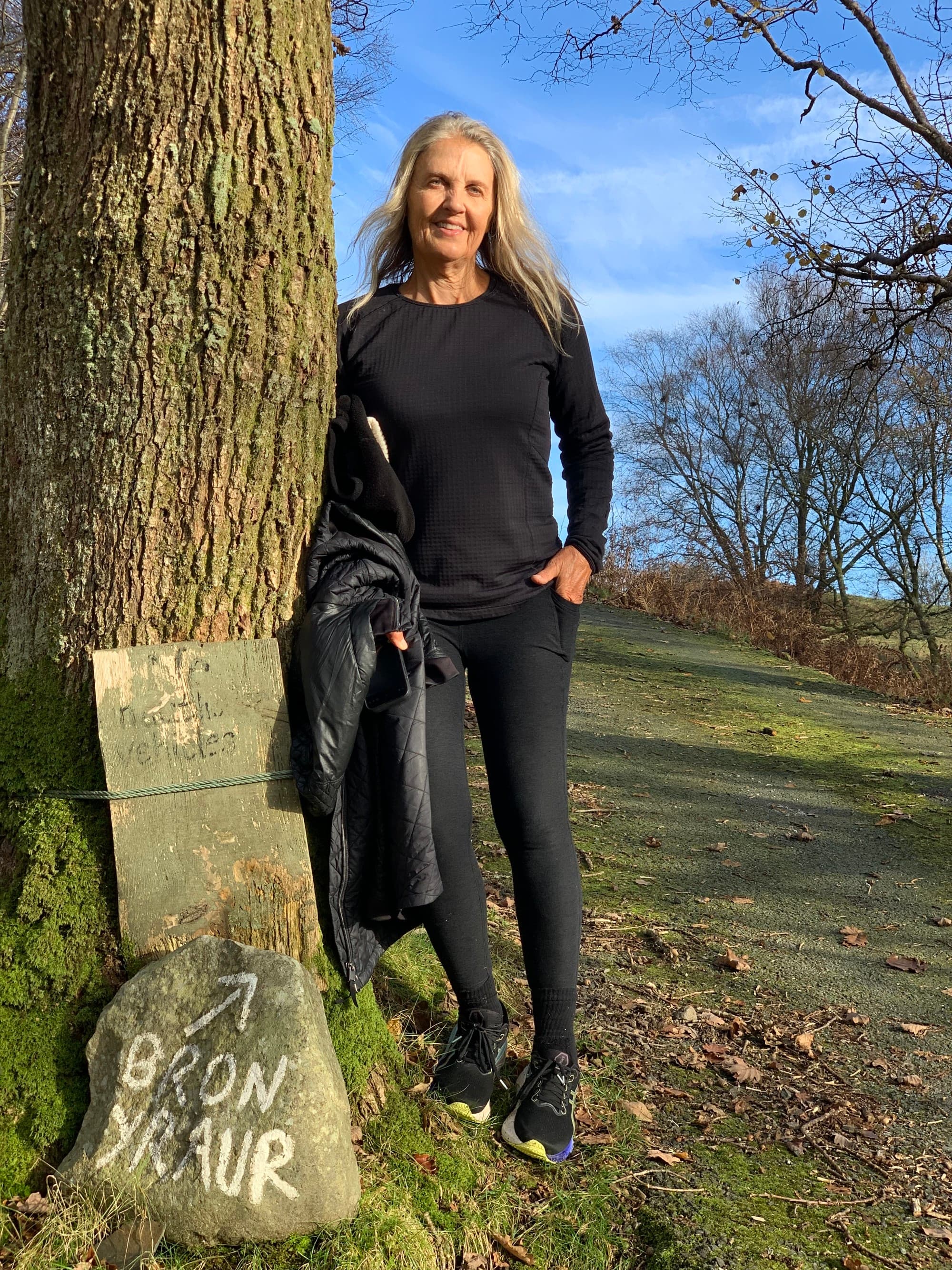 Advisor posing in front of a milestone and a tree.