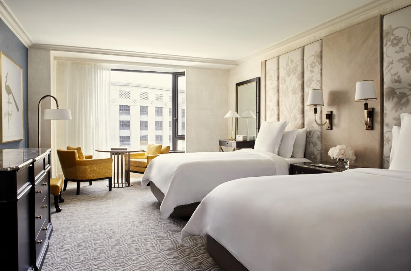 white and neutral guest room with two white beds and modern decor with a window