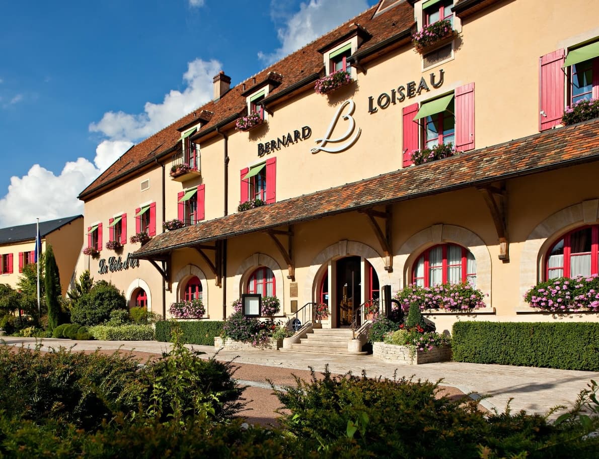 exterior of a hotel with tan stucco and red shutters