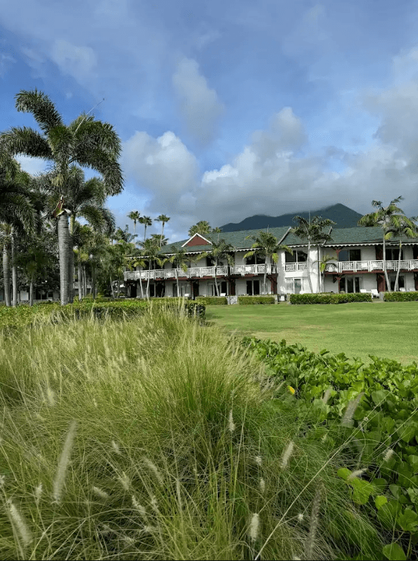 Resort View of a large green lawn, palm trees and grass surrounding the Four Seasons Resort Nevis during the day.