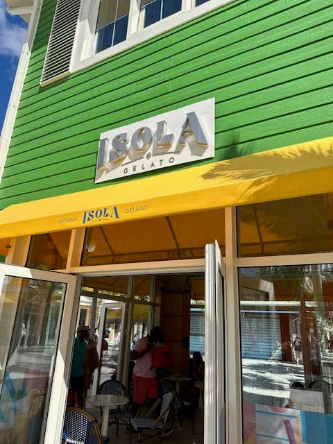 The entrance to a building with a green roof and yellow awning. The sign reads: Isola.