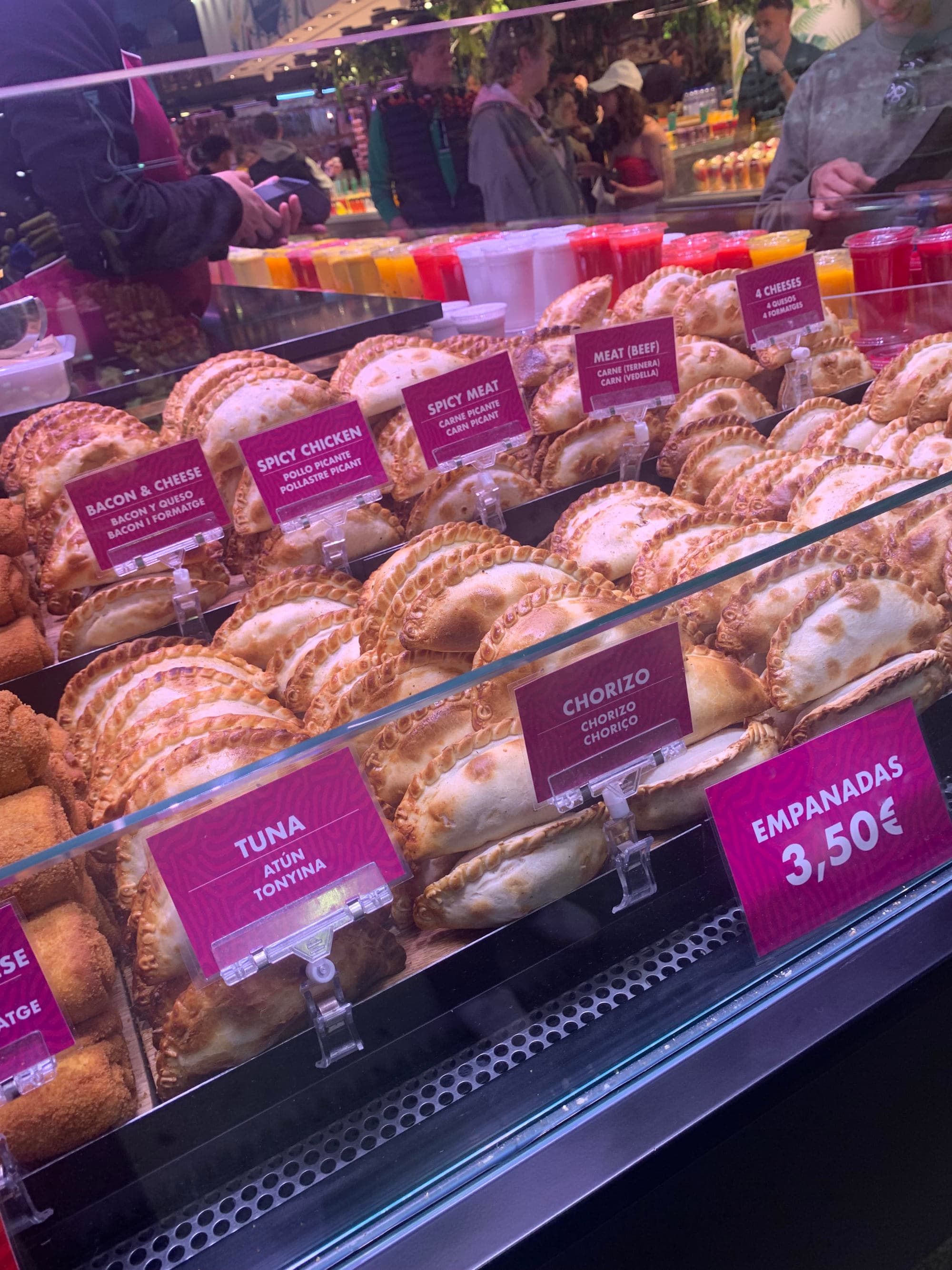 A glass case of empanadas with a price sign.