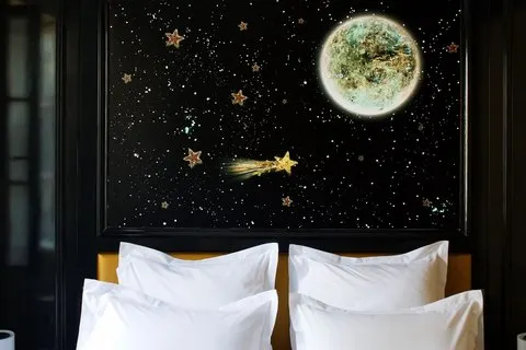 white pillows on a bed in front of a wall decorated with a mural of stars and the moon