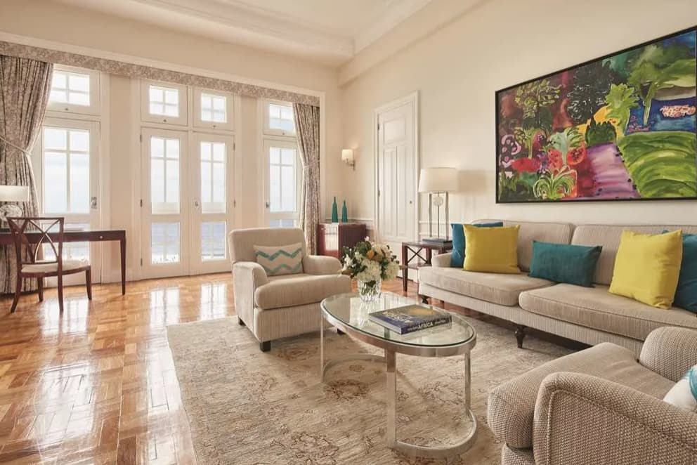 hotel room with a colorful couch and polished floors and glass French doors leading outside