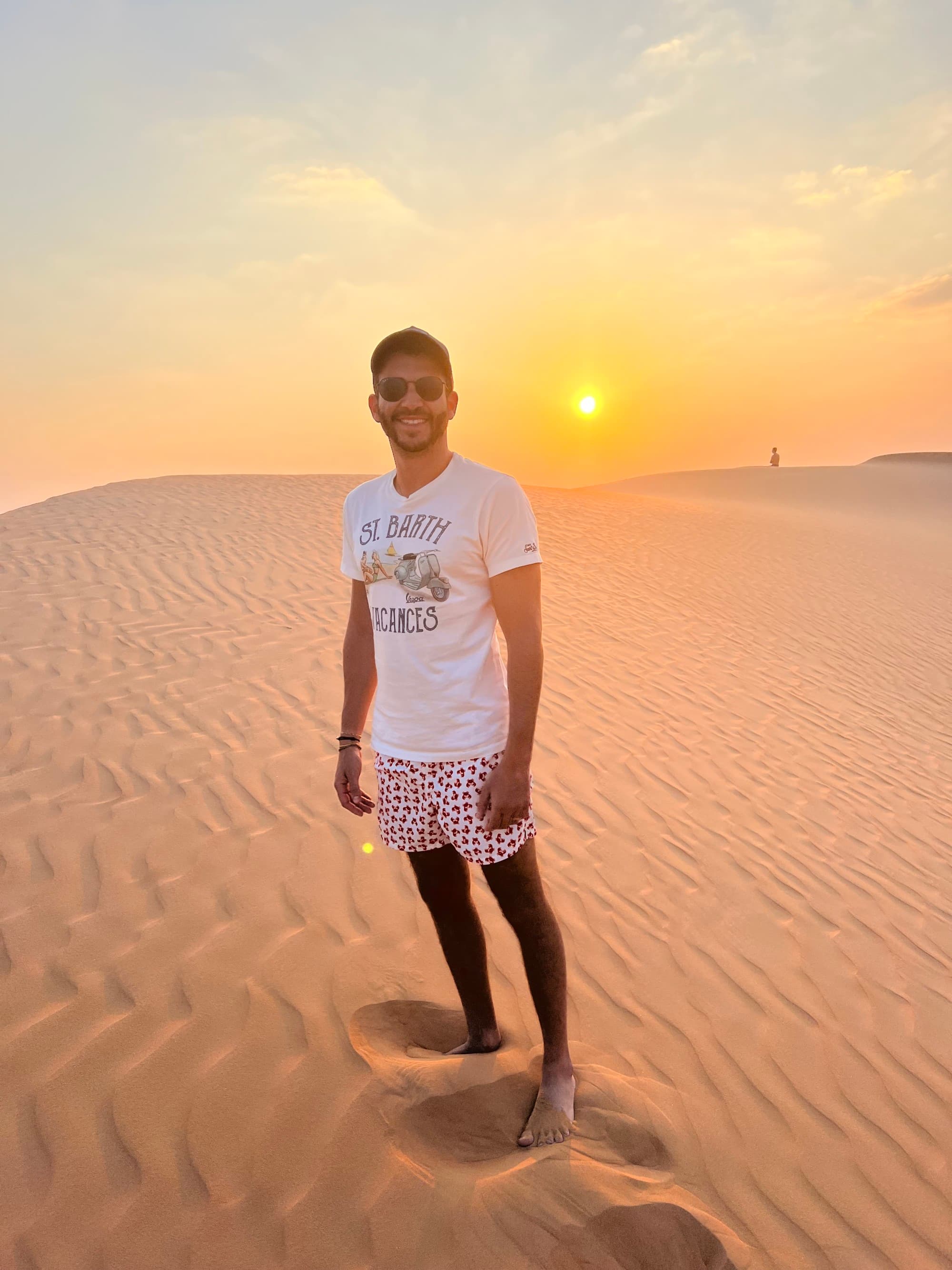 a man stand in a sandy desert at sunset