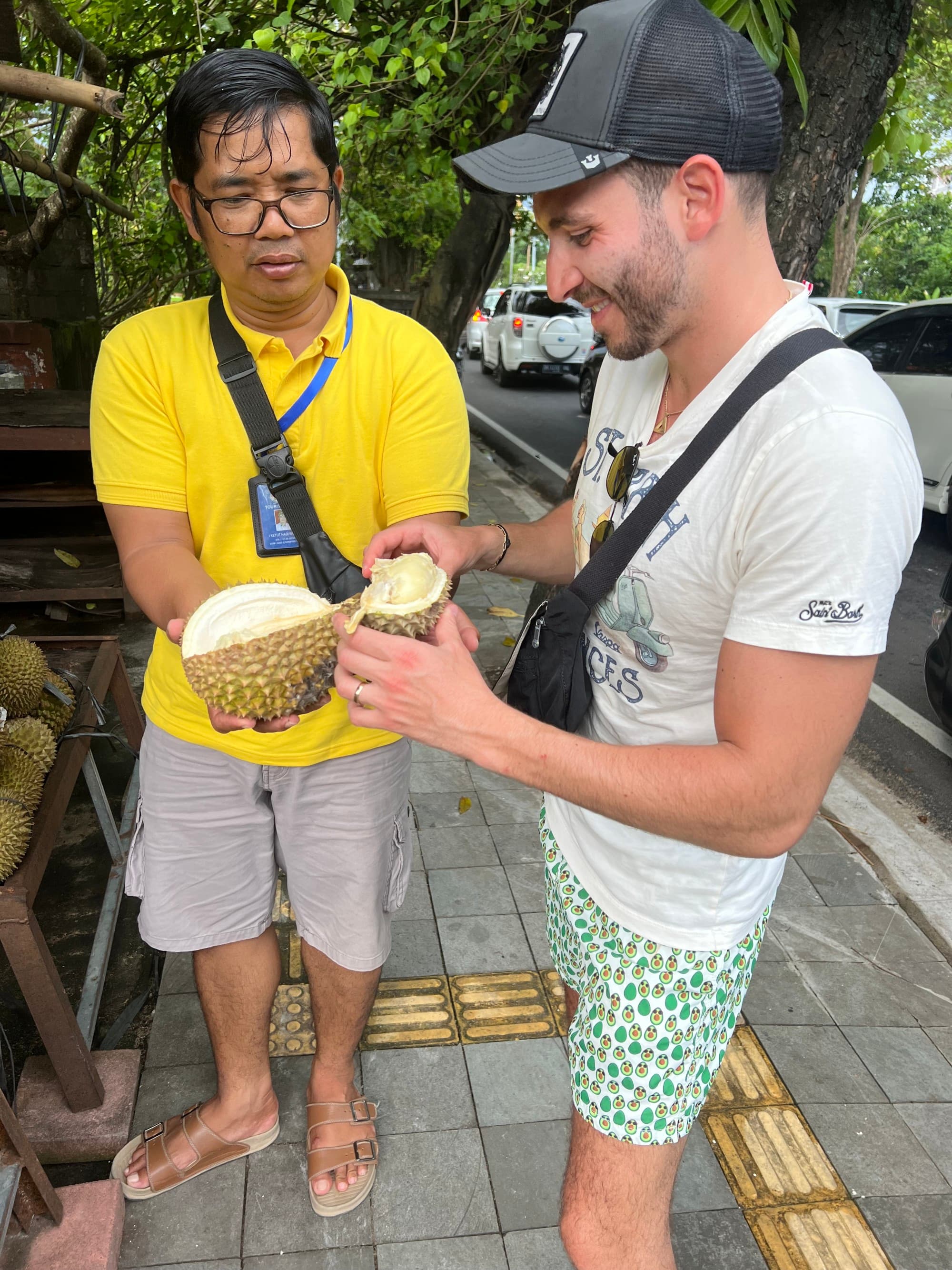 two men hold a large piece of fruit on the street