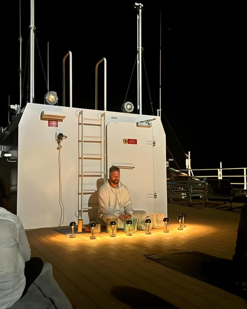 A man leading a sound bath session outdoors at night.
