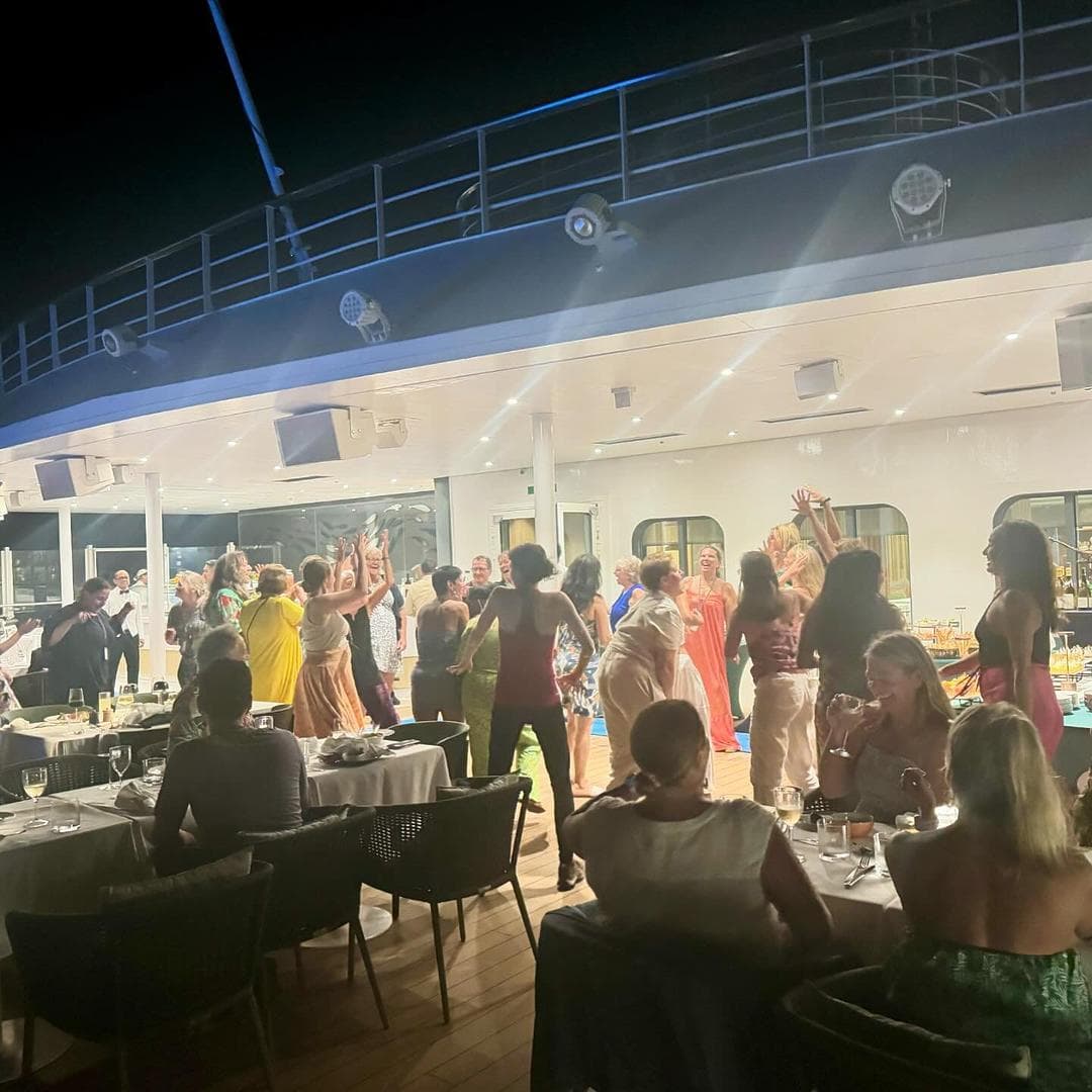 Passengers dancing on the outdoor deck of the ship.