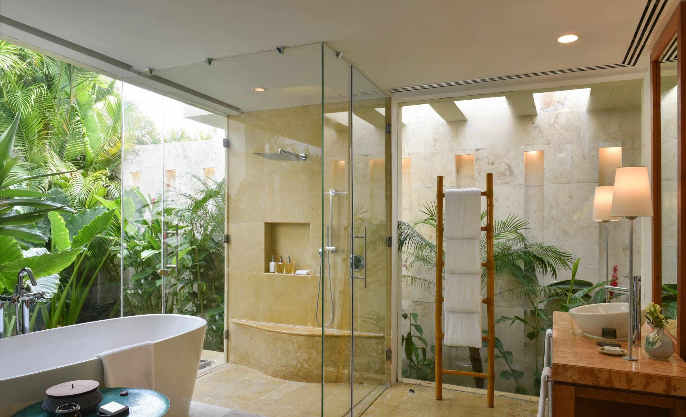 bathroom with soaking tub, clear glass shower and open garden with tropical plants