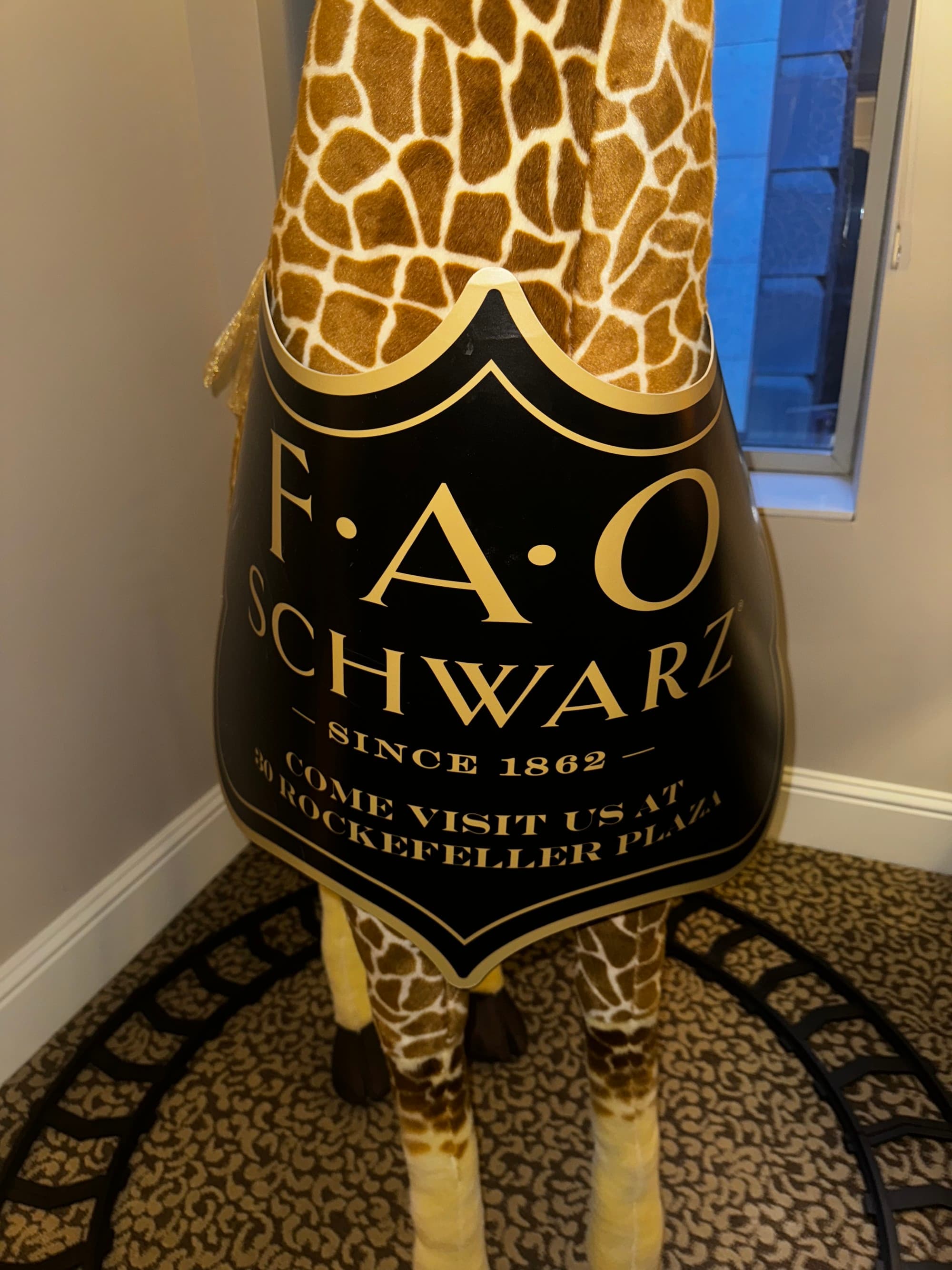 A large plush giraffe with an "FAO Schwarz" tag on it