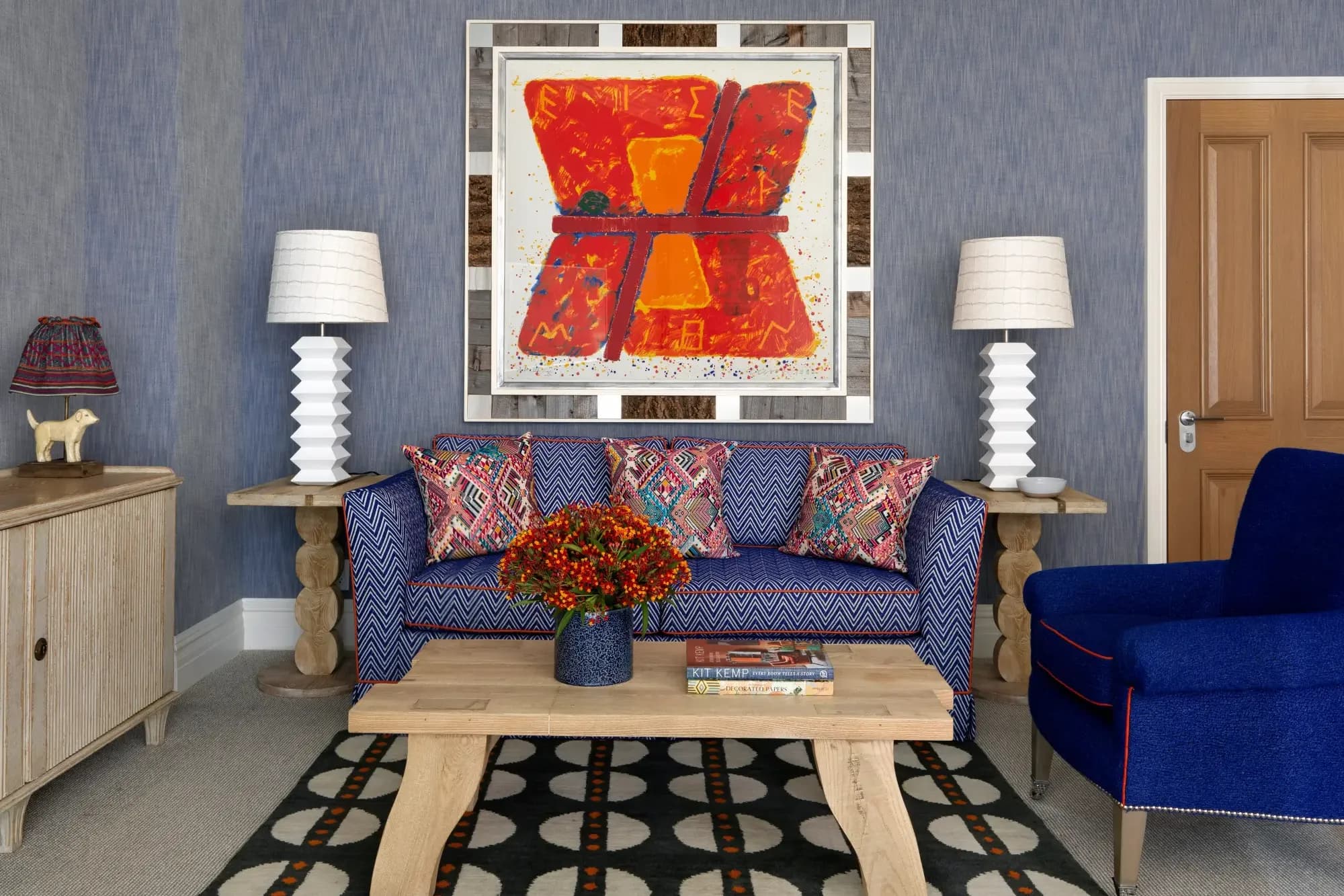 a funky seating area with blue furniture and a red abstract painting