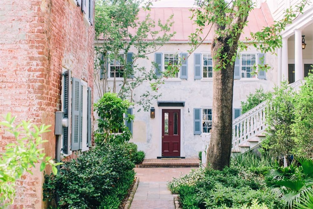 white and brick hotel exterior with brick pathway and tree