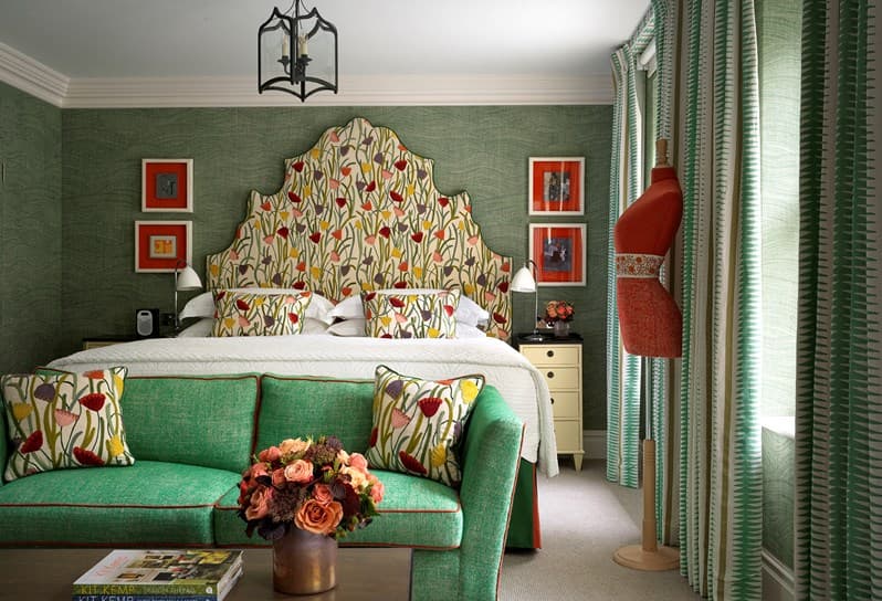 a bed with an oversized headboard covered in floral fabric