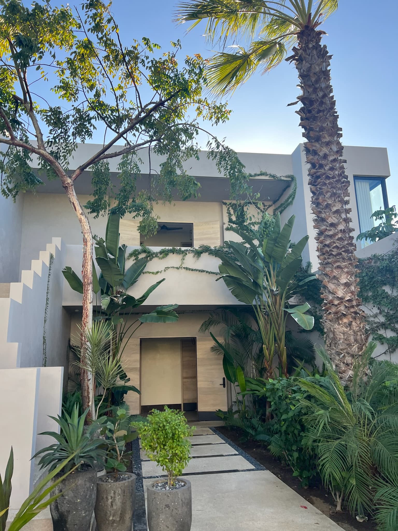 An exterior view of one of the resorts rooms with a pathway lined with tropical flora, leading to the room's private entrance.