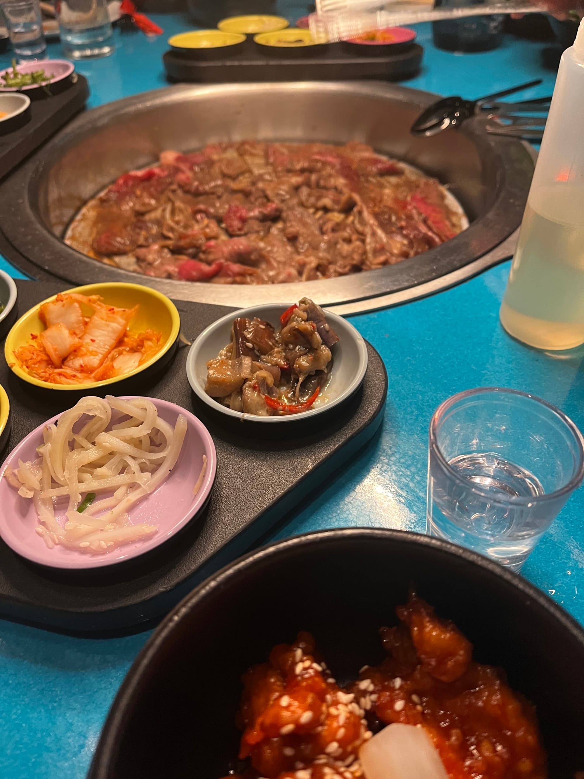 A view of a dinner with a main grill in the middle of the table and side dishes