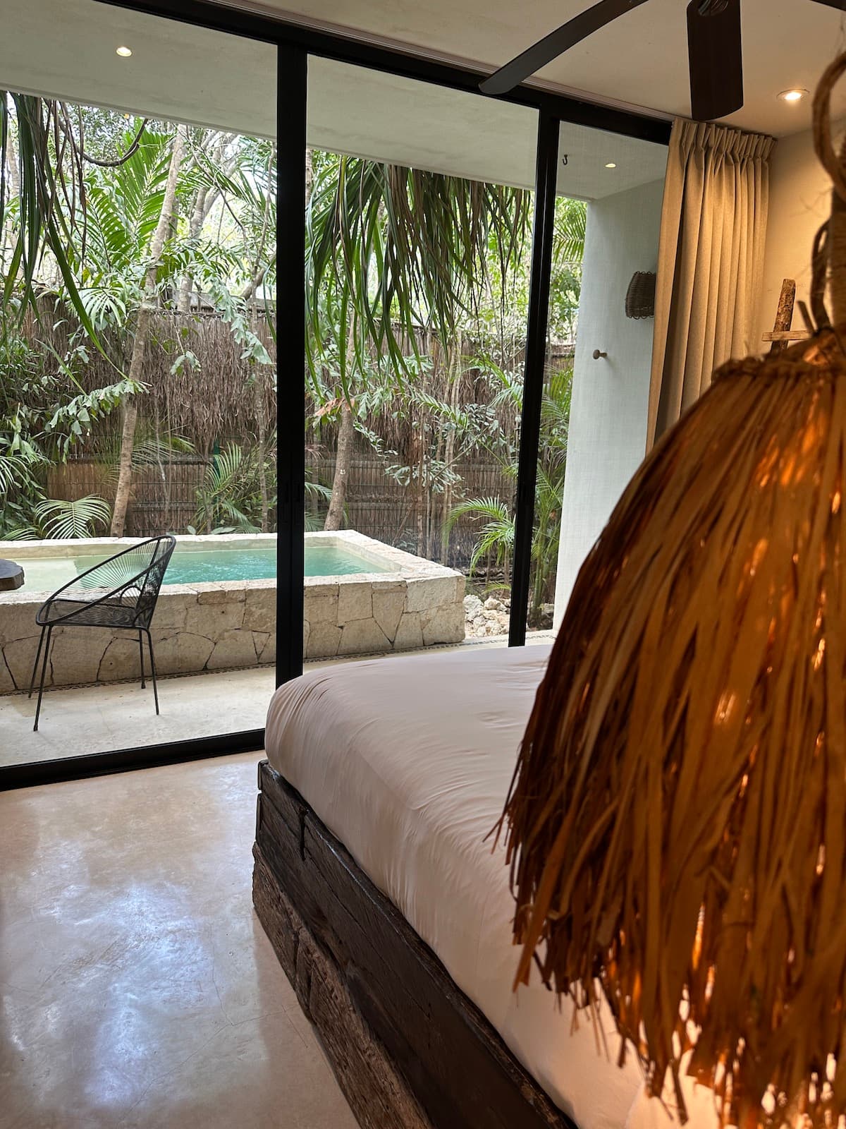 A hotel room with floor-to-ceiling windows looking out onto a pool area