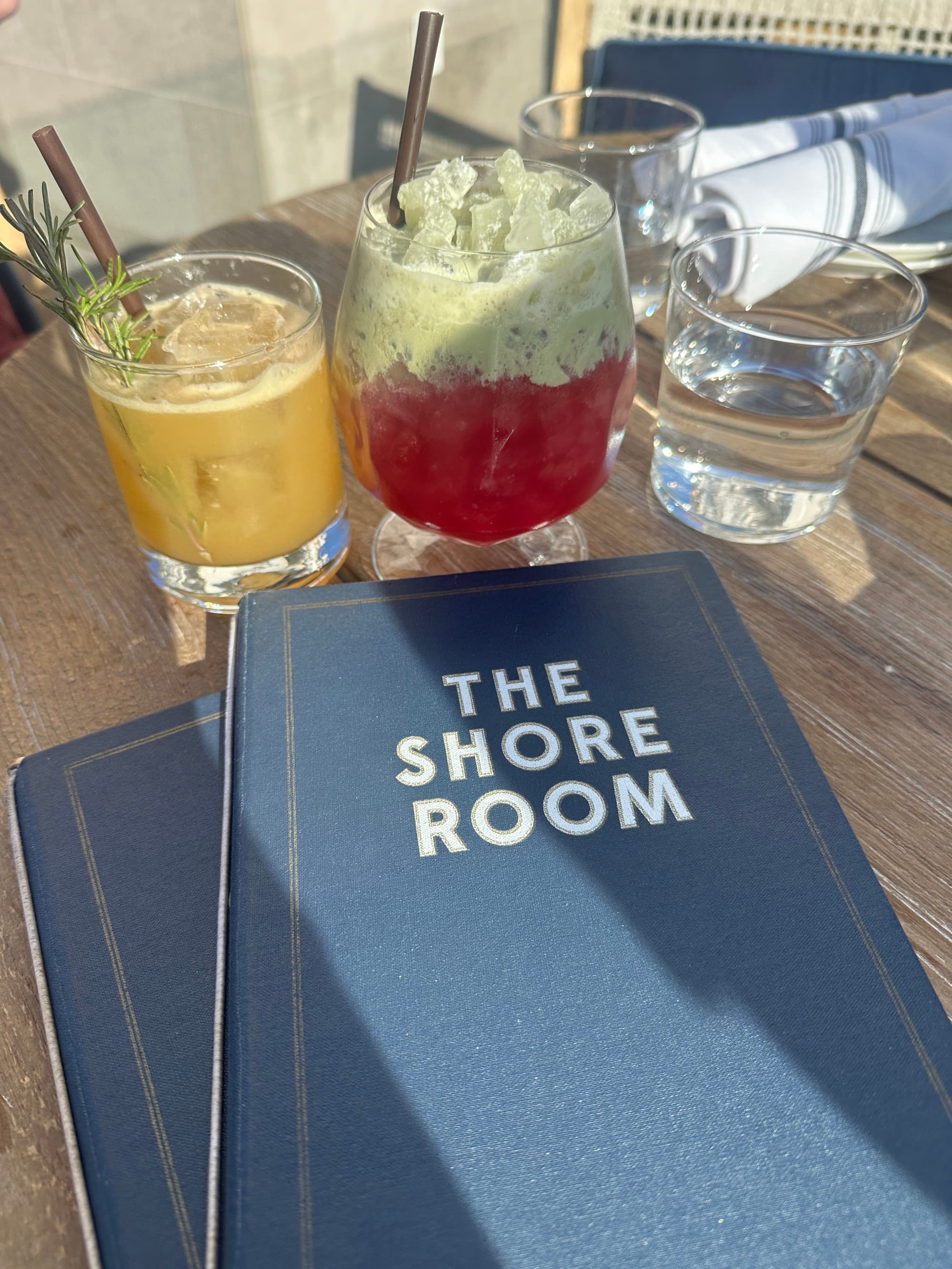 Two drinks and a menu reading "The Shore Room" sitting on a wooden table