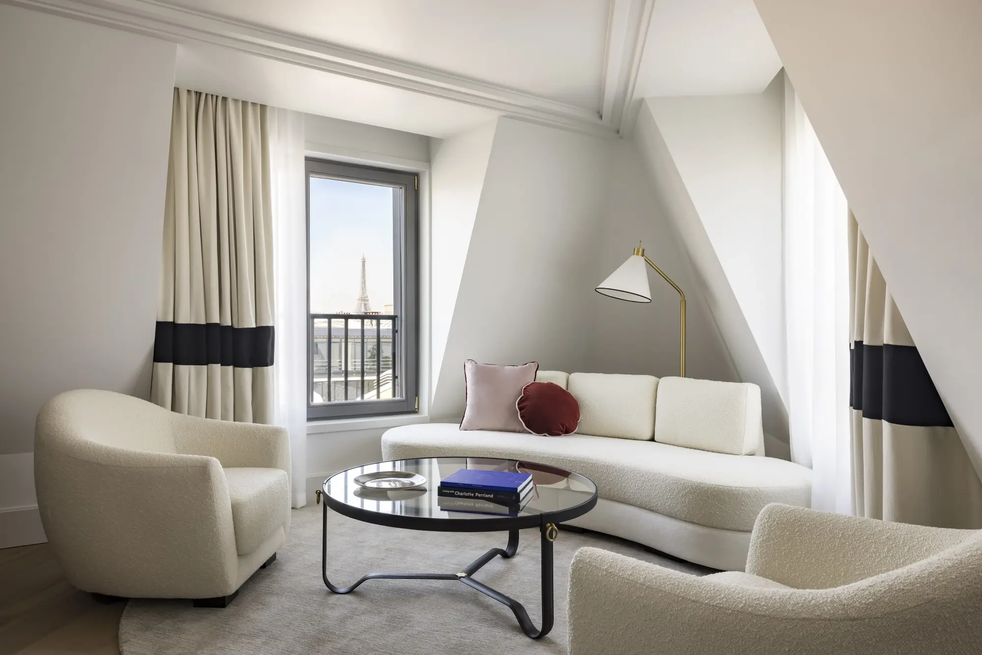 a sleek living room with white furniture and a few of the Eiffel Tower outside a large window