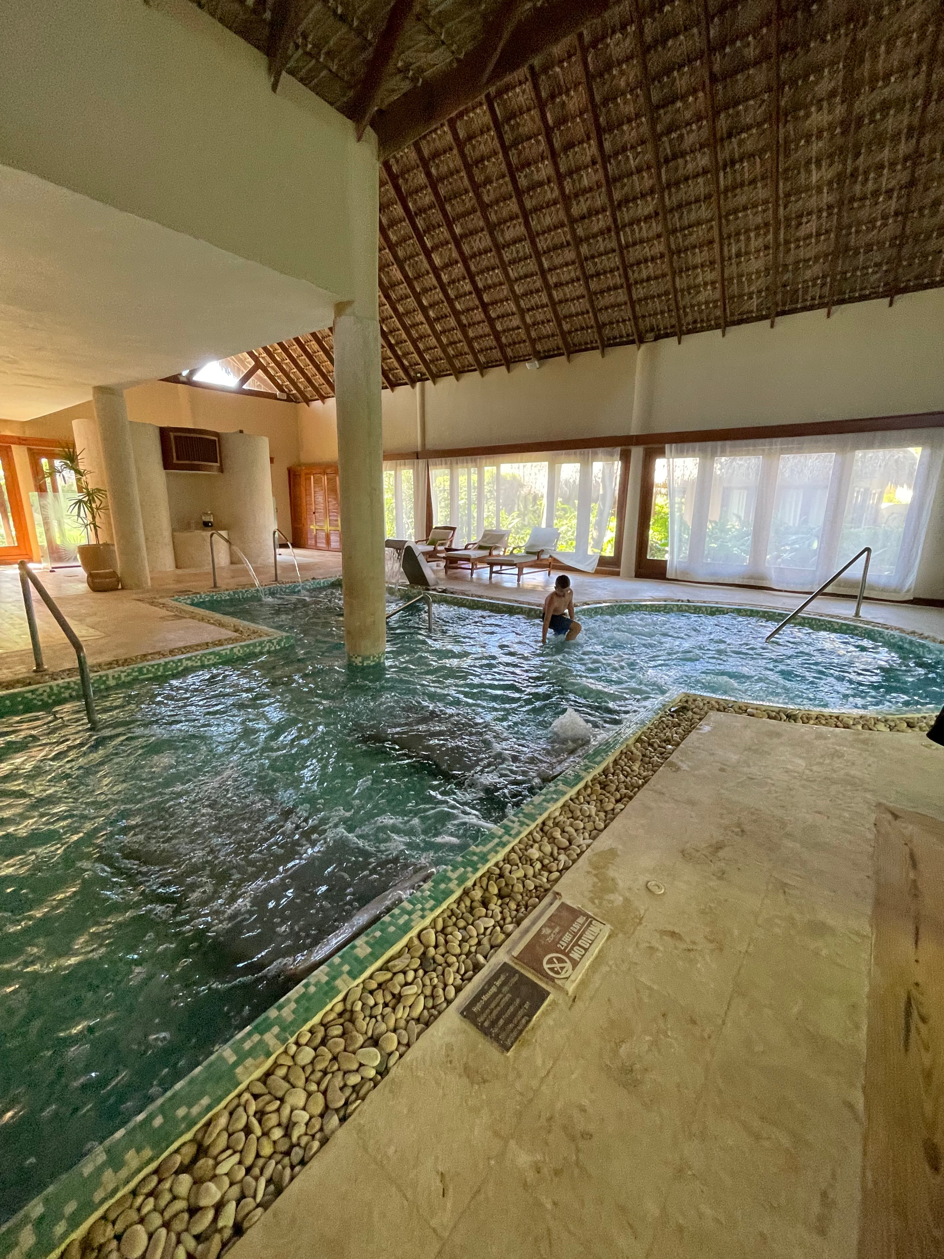 An indoor pool with a child entering the attached jacuzzi