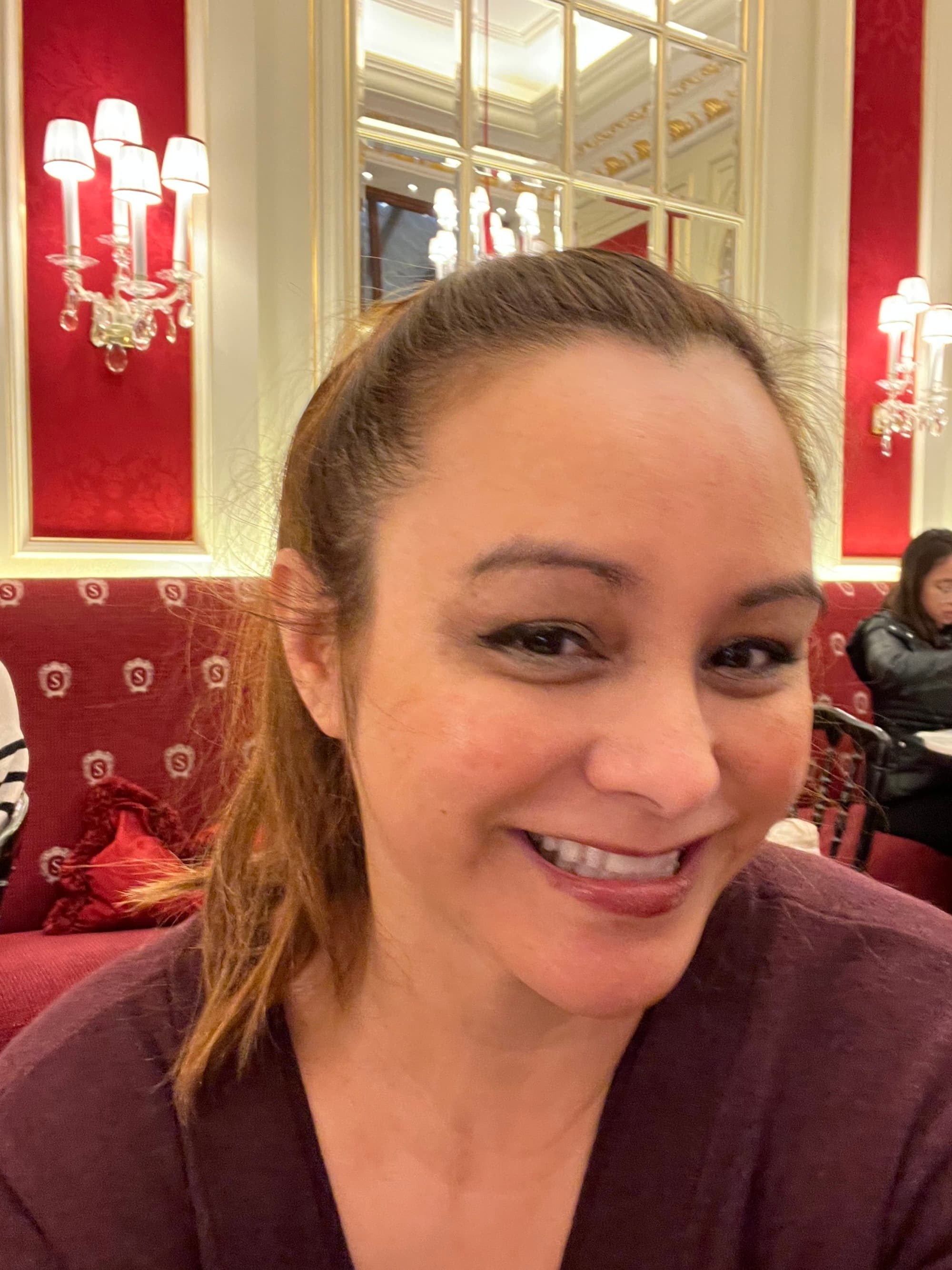 A selfie of Fora Advisor April at Café Sacher, with red walls and furniture behind her