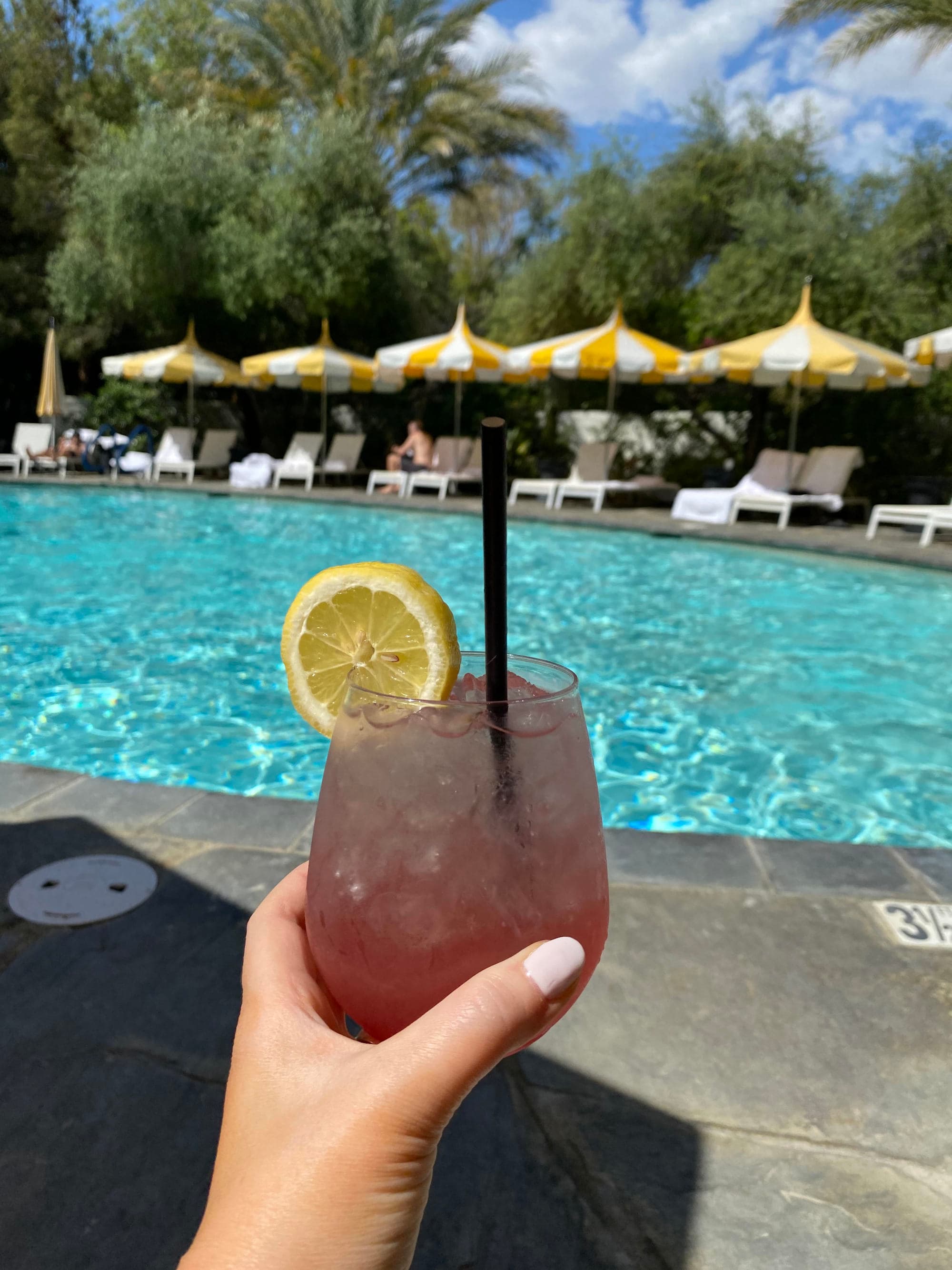Tropical drink with a pool and loungers in the distance on a sunny day