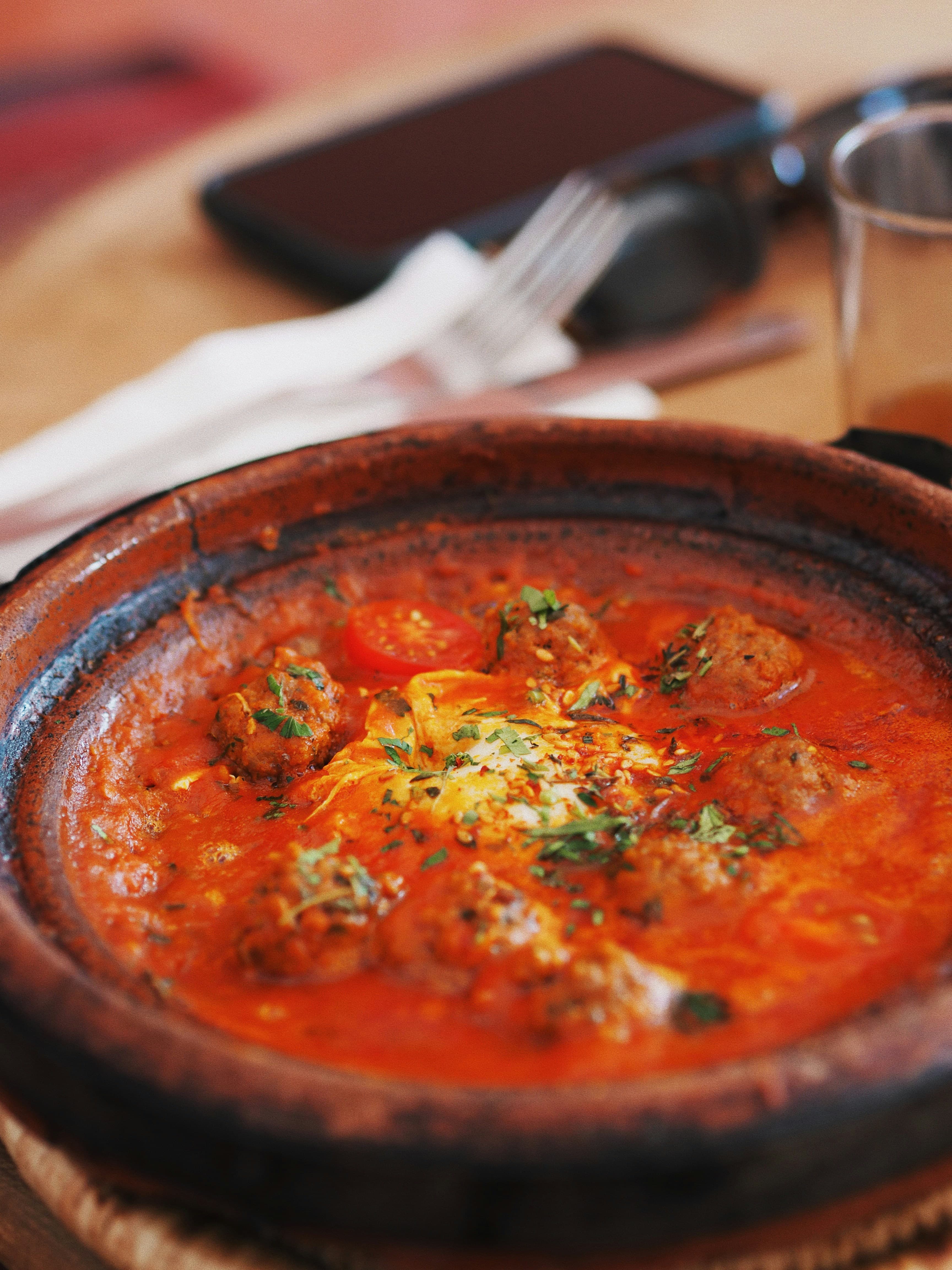 A close up view of traditional kefta tagine stew in a clay bowl.