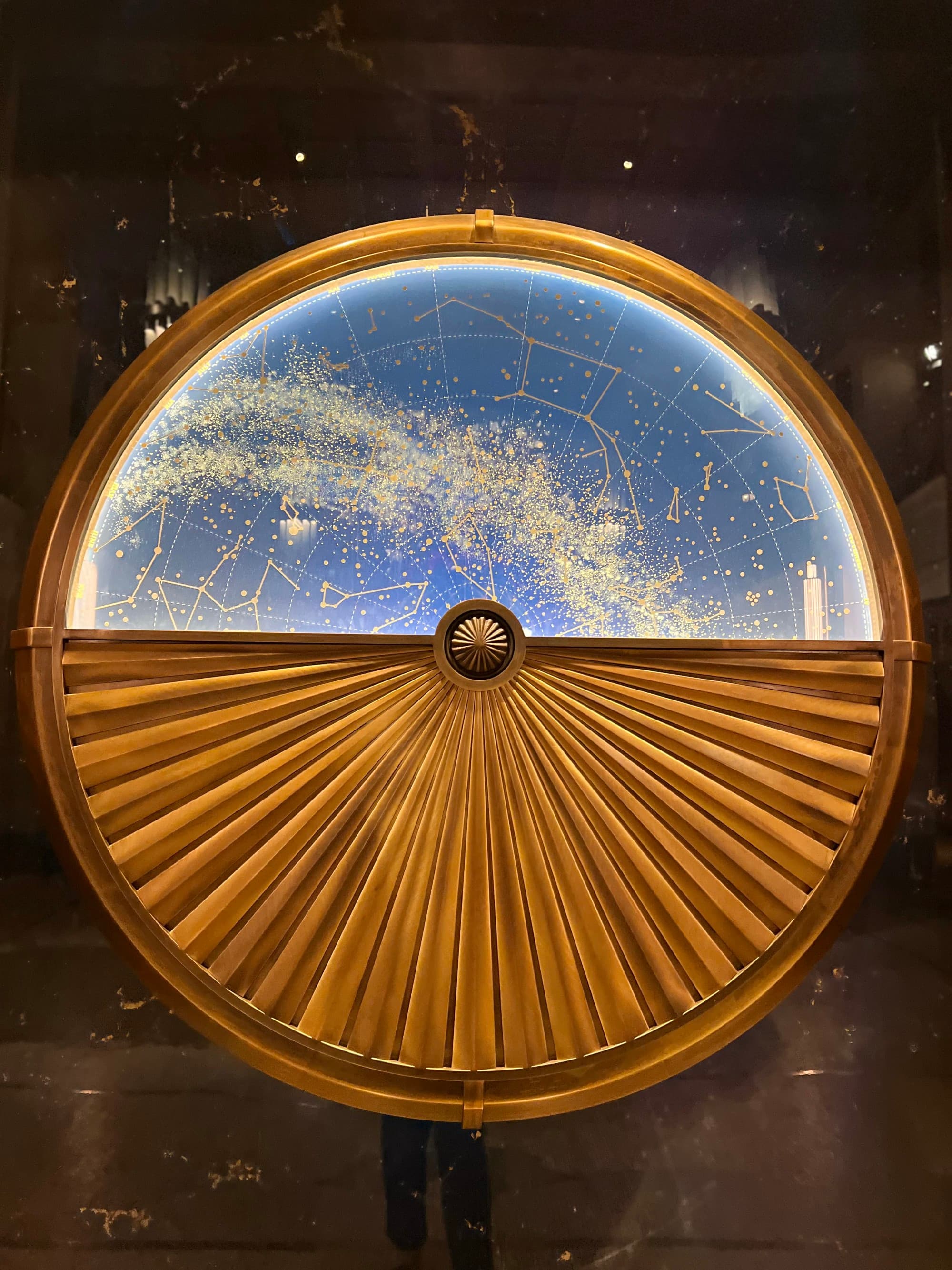 Art in the lobby of a hotel, a circular structure with a gold outline, one half in gold folds and the other in blue