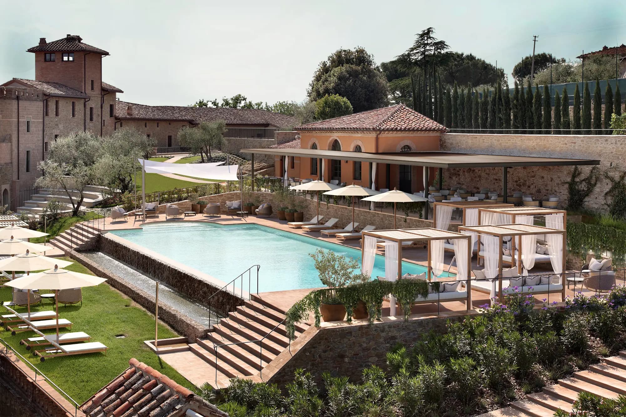 a luxe countryside estate composed of several stone buildings with a pool and poolside cabañas and lounge chairs