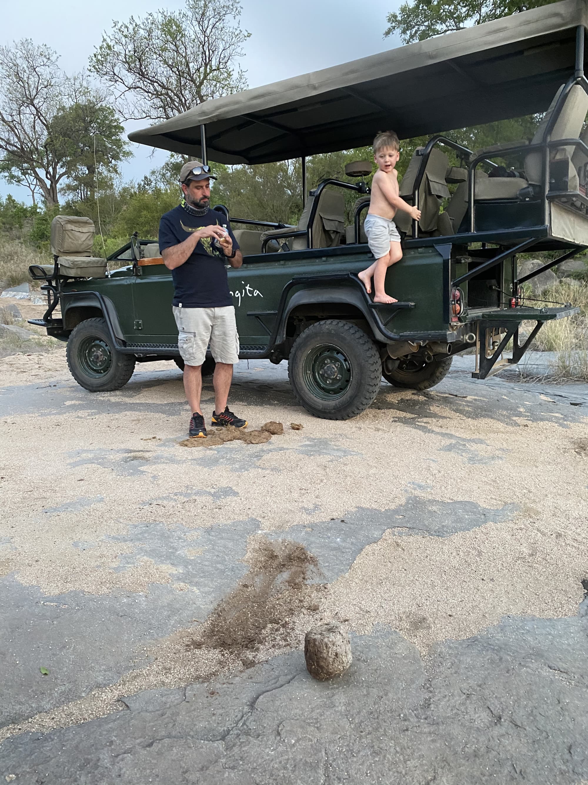A man standing by a safari and a child climbing aboard.