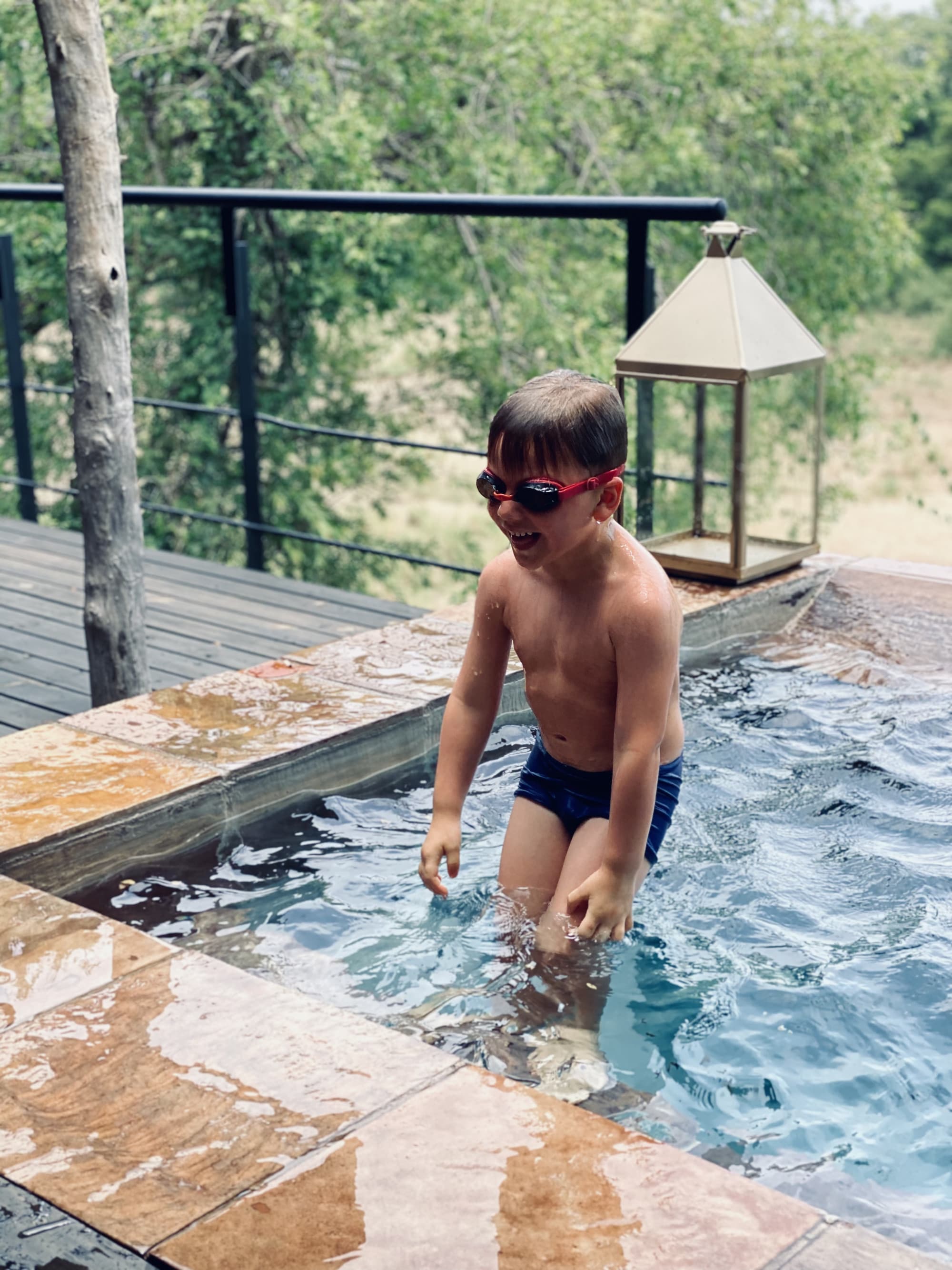 Child in a plunge pool on a hotel terrace wearing goggles
