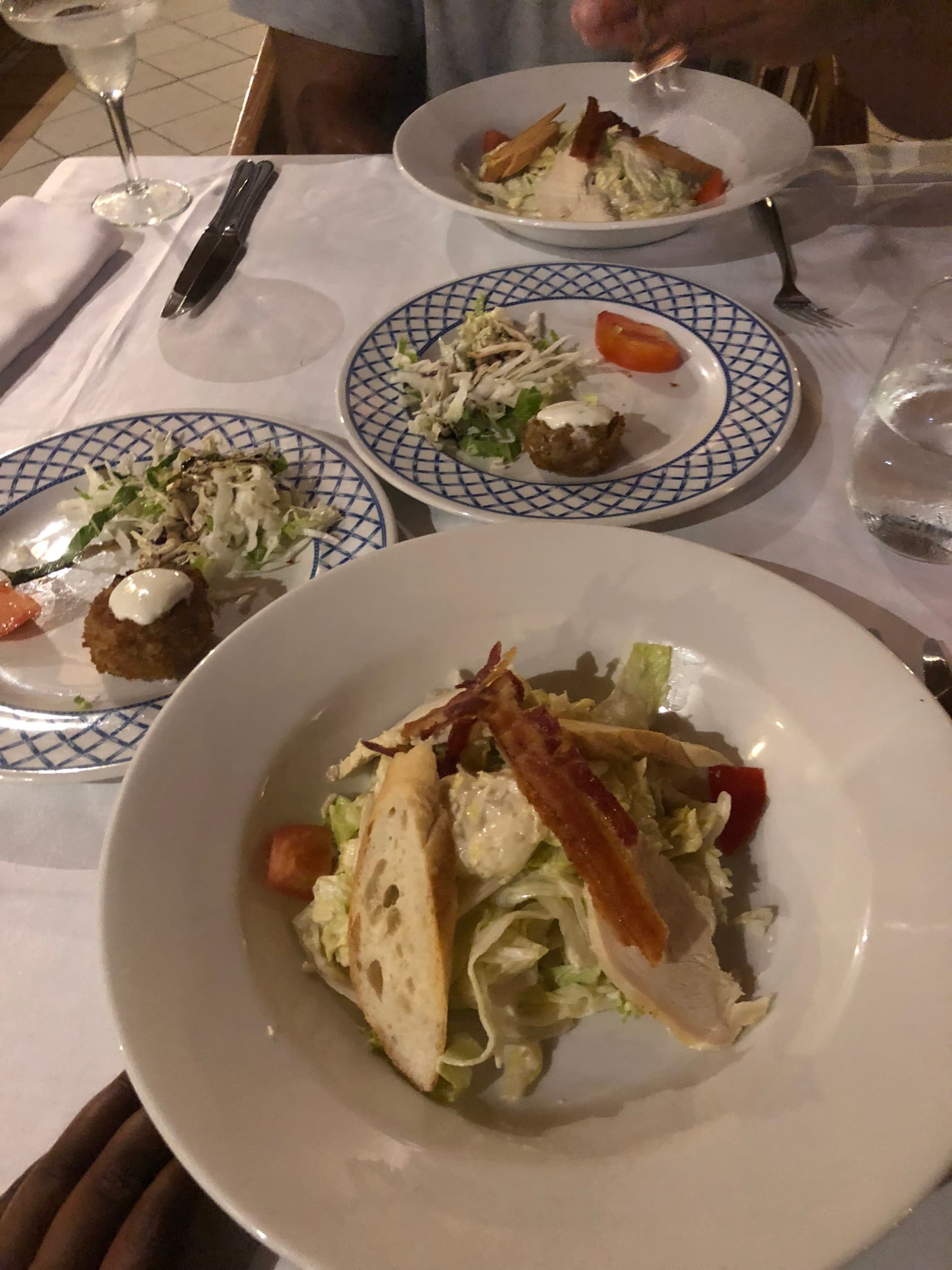 Four plates of food displayed beautifully at a restaurant on top of a white table.